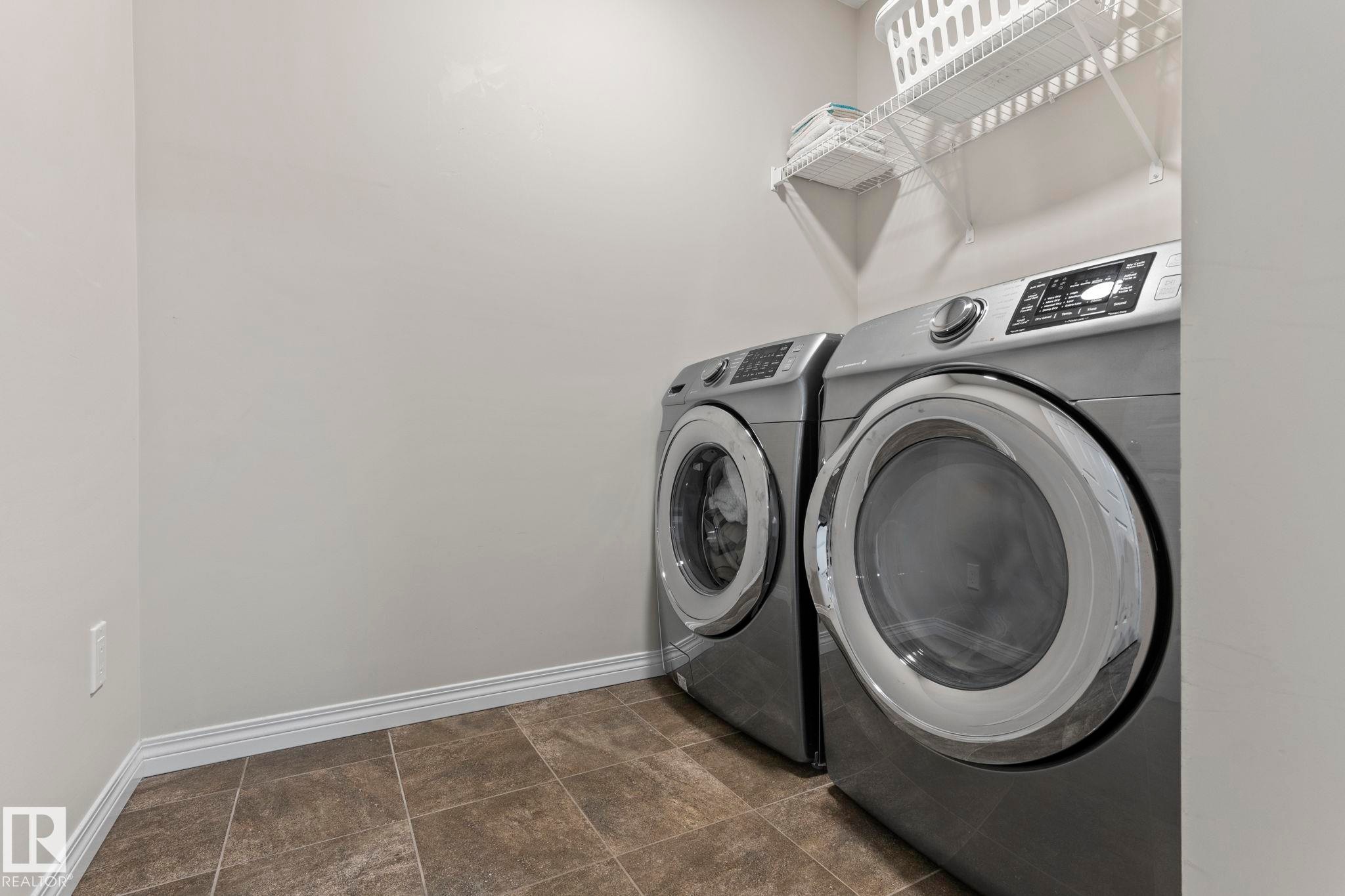 Dedicated laundry area featuring tile flooring, white baseboards, and wire shelving - 2131 51 Sw, Edmonton, AB - Indoor Photo Showing Laundry Room