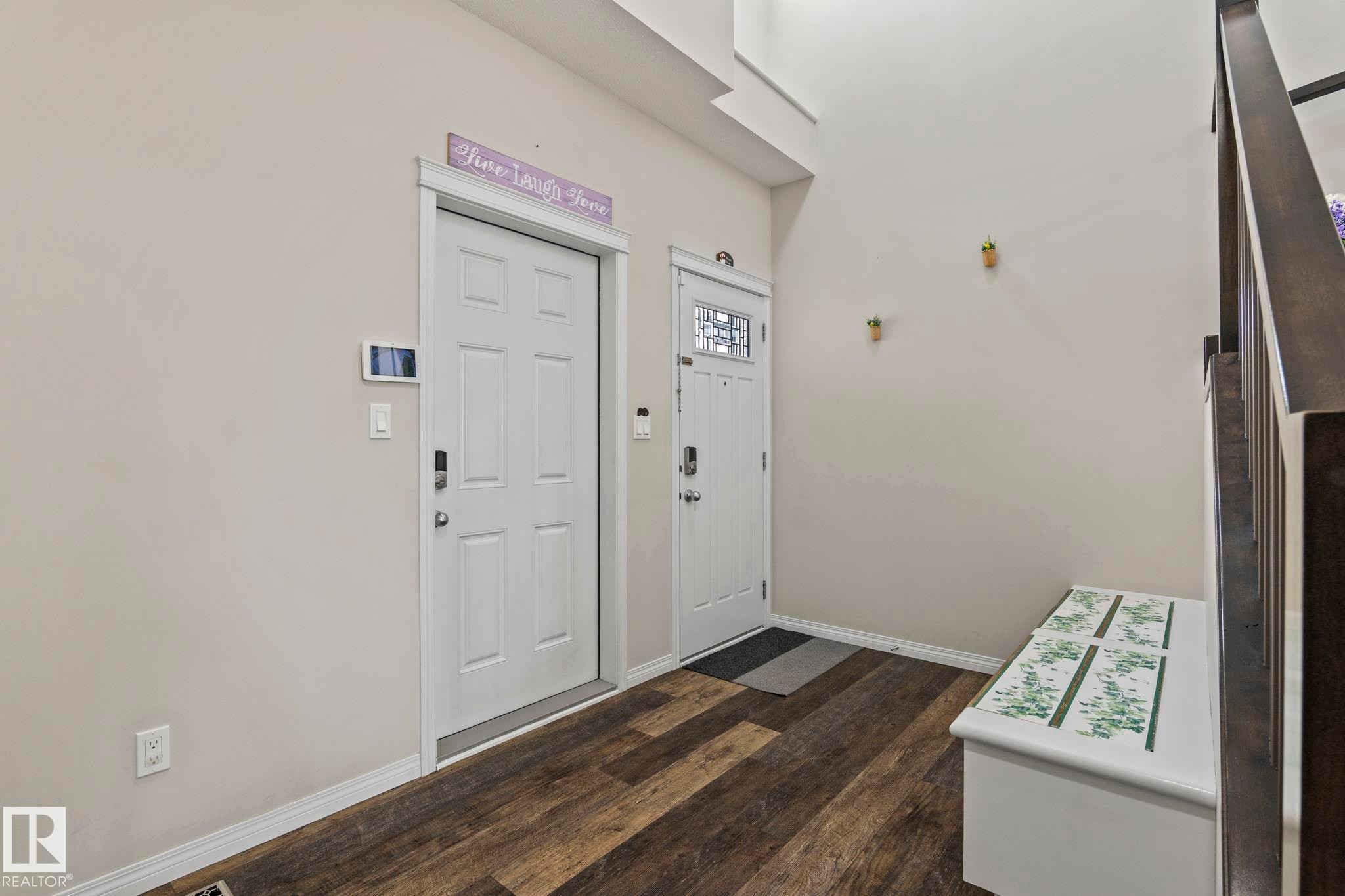 Entryway featuring wood-finish flooring, white trim, and a staircase with dark wood newel posts - 2131 51 Sw, Edmonton, AB - Indoor Photo Showing Other Room