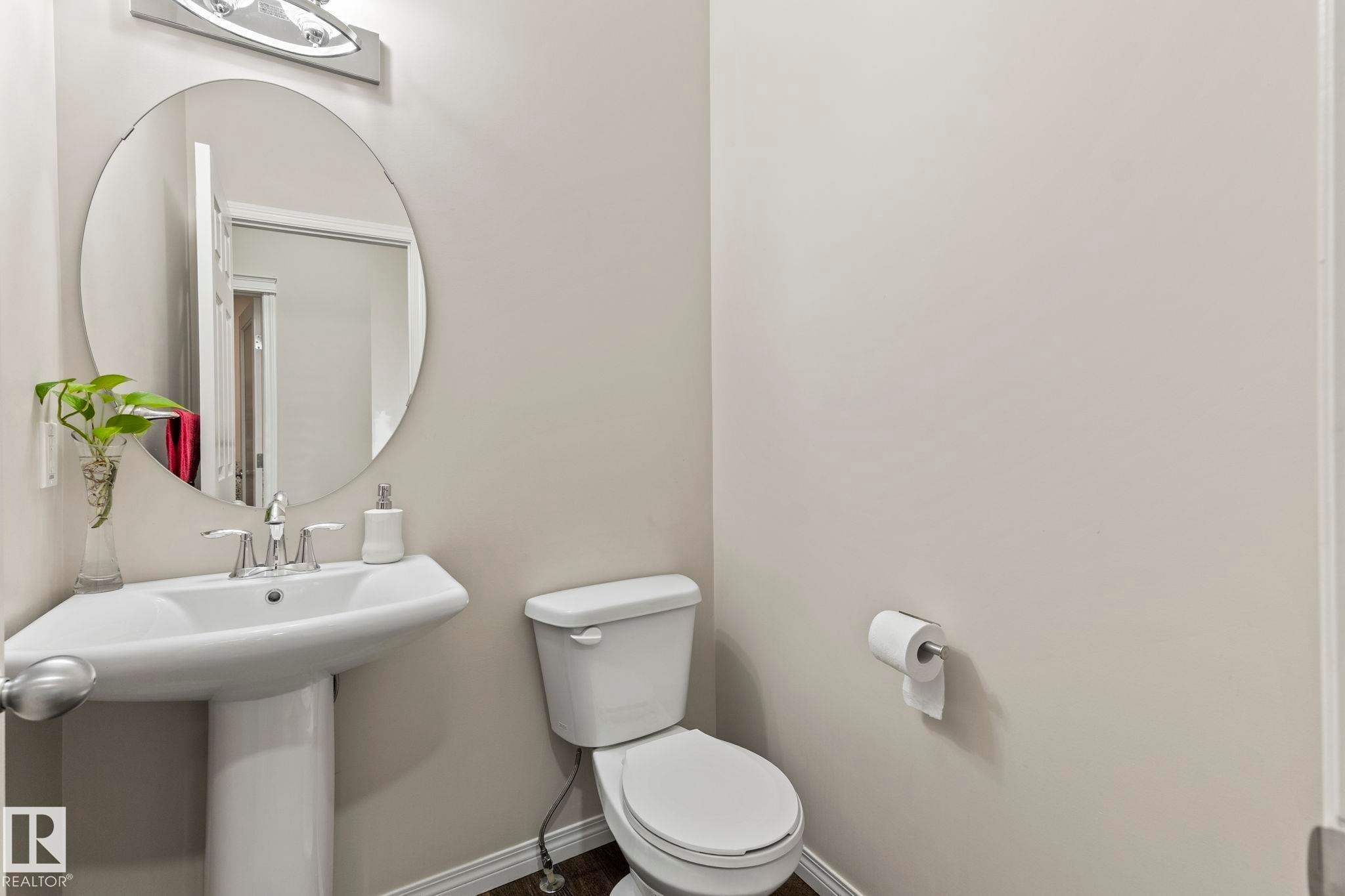 Pedestal sink featuring a chrome faucet, large circular mirror, and recessed lighting - 2131 51 Sw, Edmonton, AB - Indoor Photo Showing Bathroom
