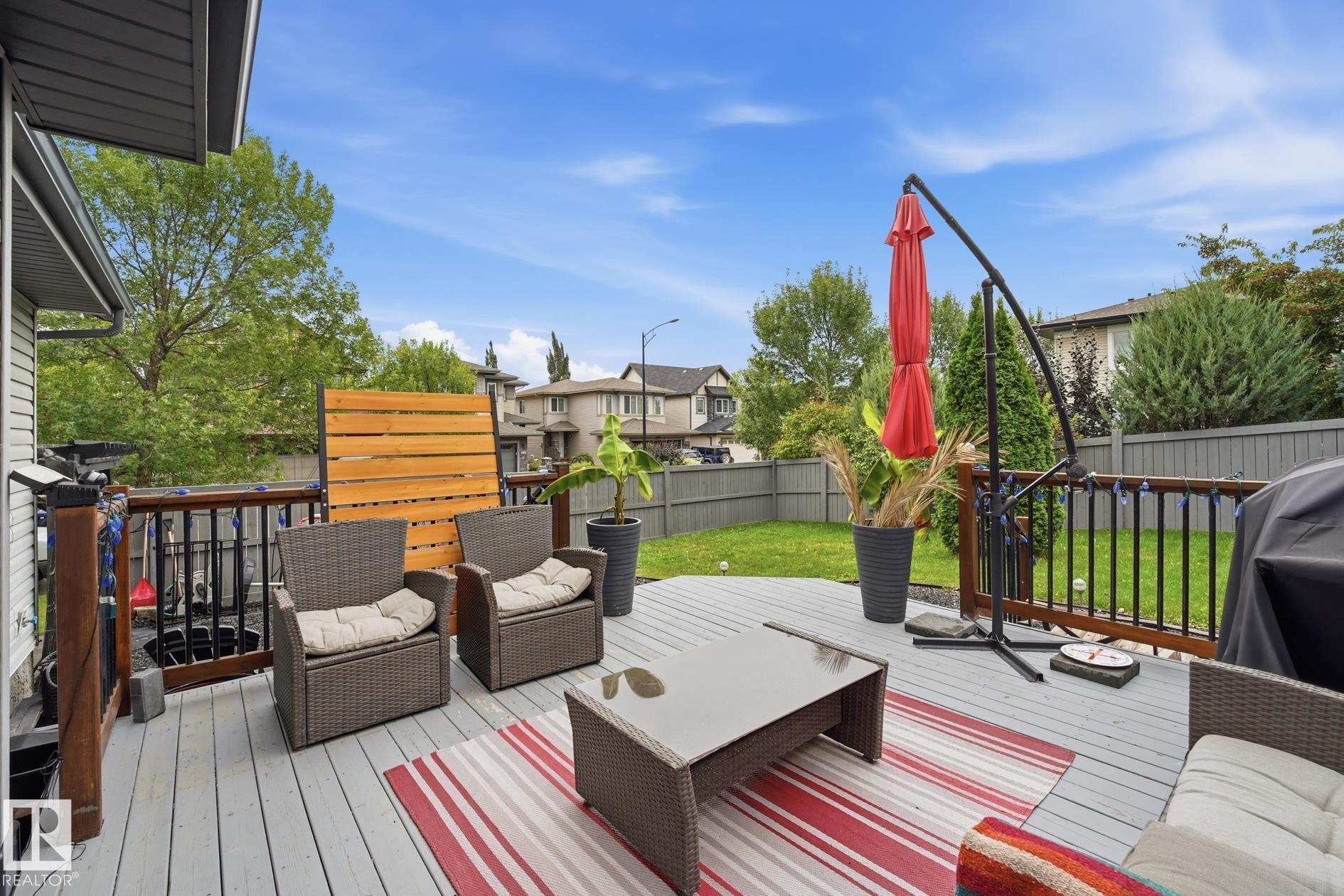 Spacious outdoor deck with a light-toned surface, dark railings, and a privacy screen - 20007 131 Avenue Nw, Edmonton, AB