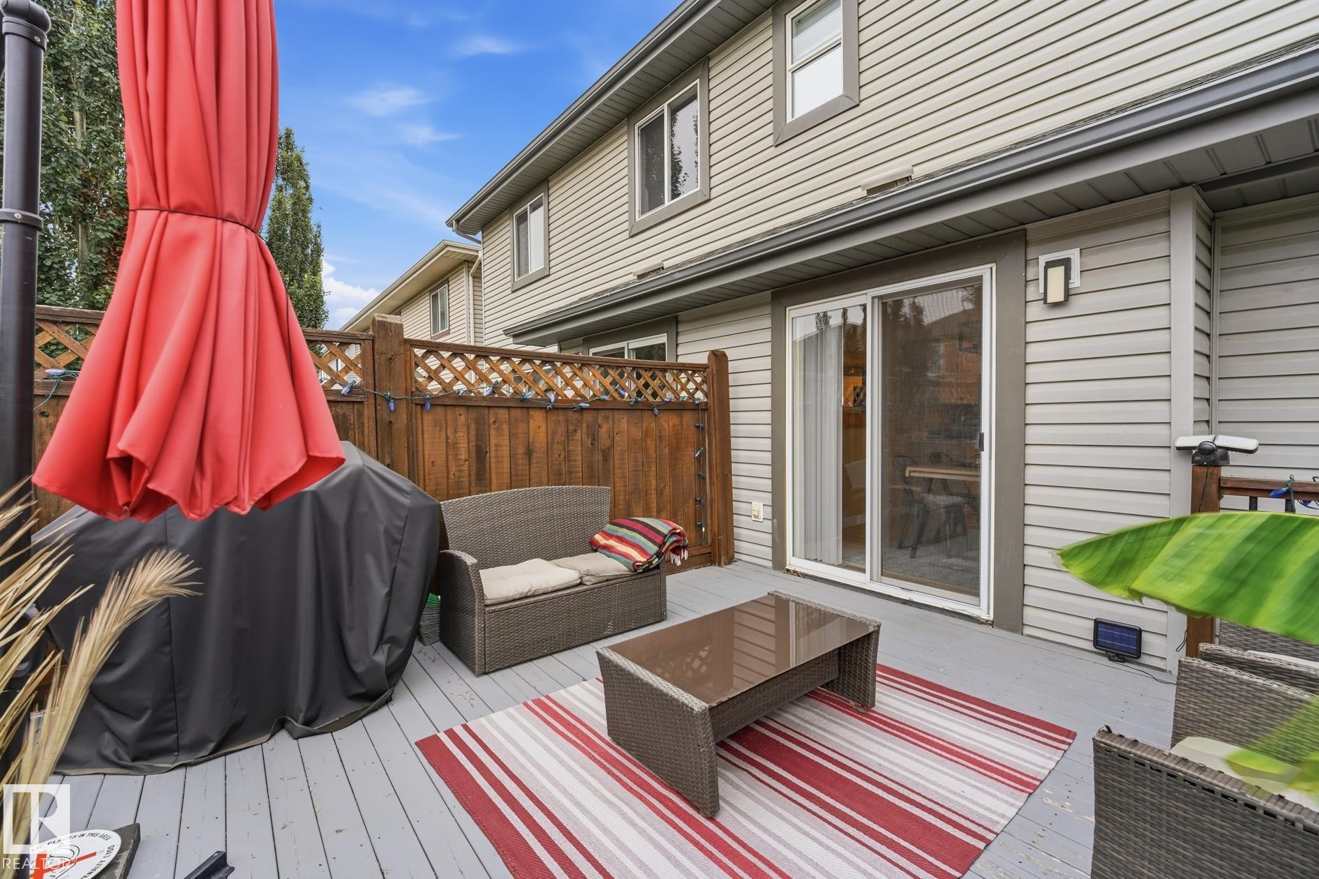 Expansive outdoor deck featuring wood-finish flooring, privacy fencing, and direct access through sliding glass doors - 20007 131 Avenue Nw, Edmonton, AB