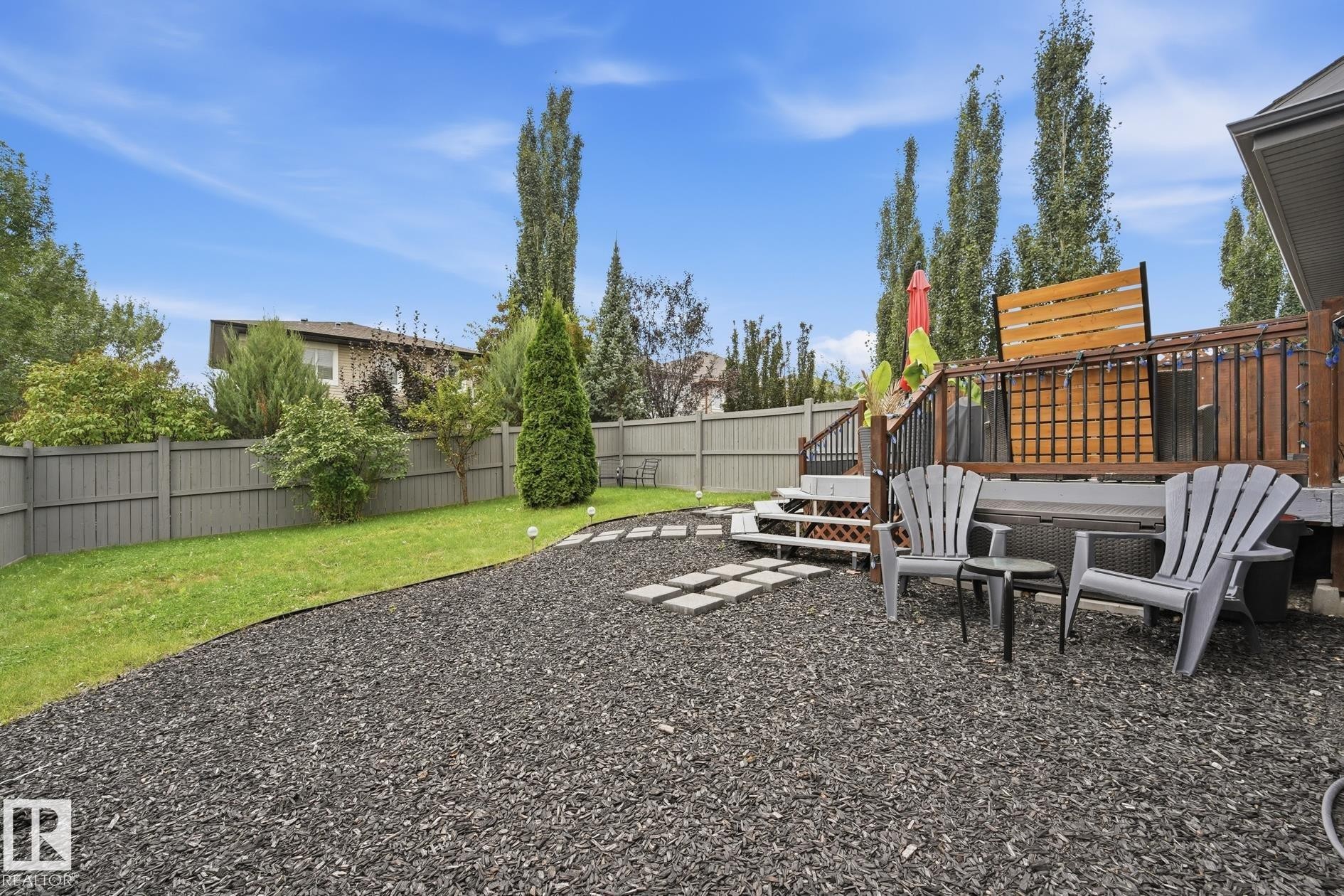 Expansive backyard featuring a multi-level wooden deck, stone paver pathway, and a well-maintained lawn - 20007 131 Avenue Nw, Edmonton, AB