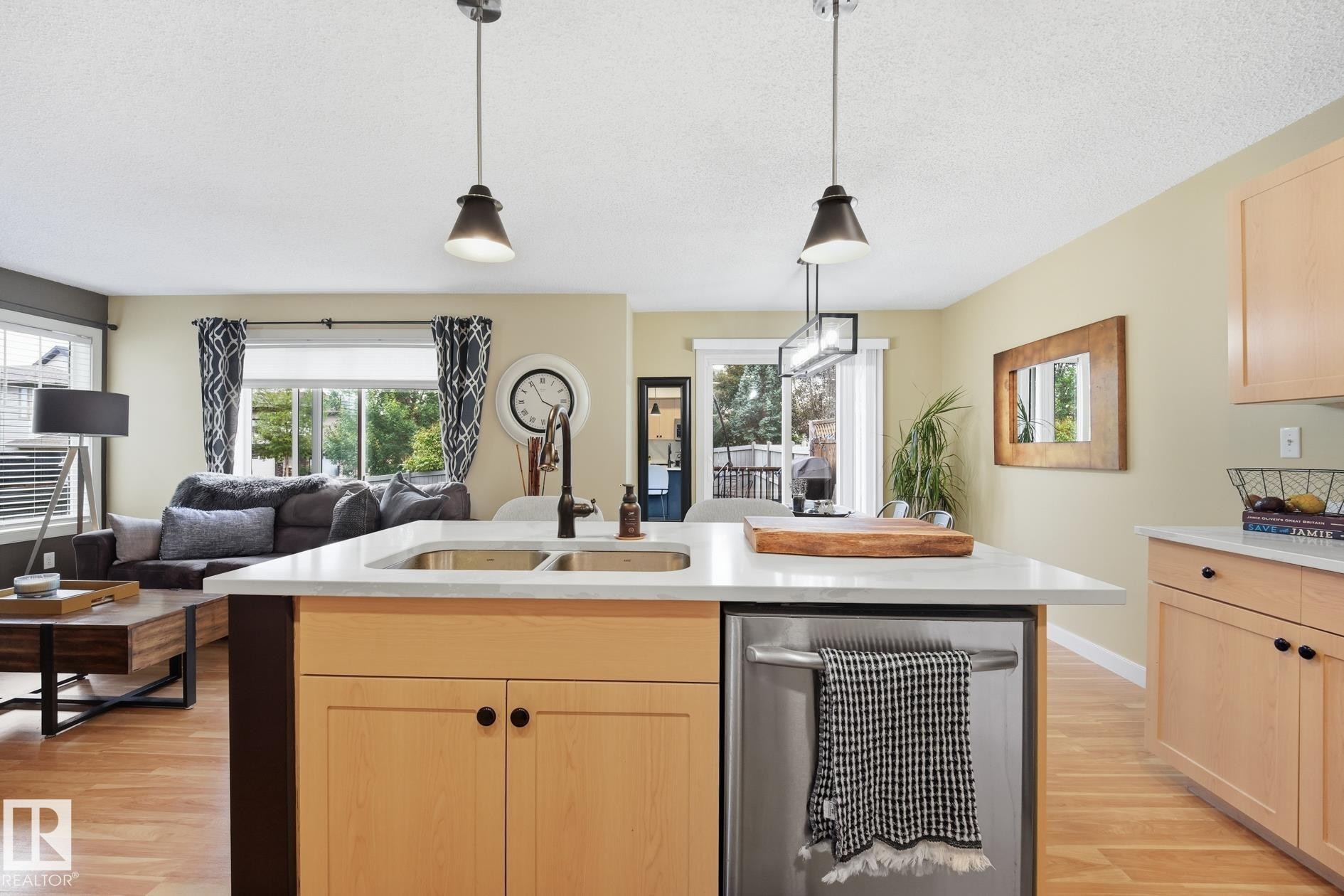 Kitchen island with a double basin sink, stainless steel appliances, and pendant lighting - 20007 131 Avenue Nw, Edmonton, AB