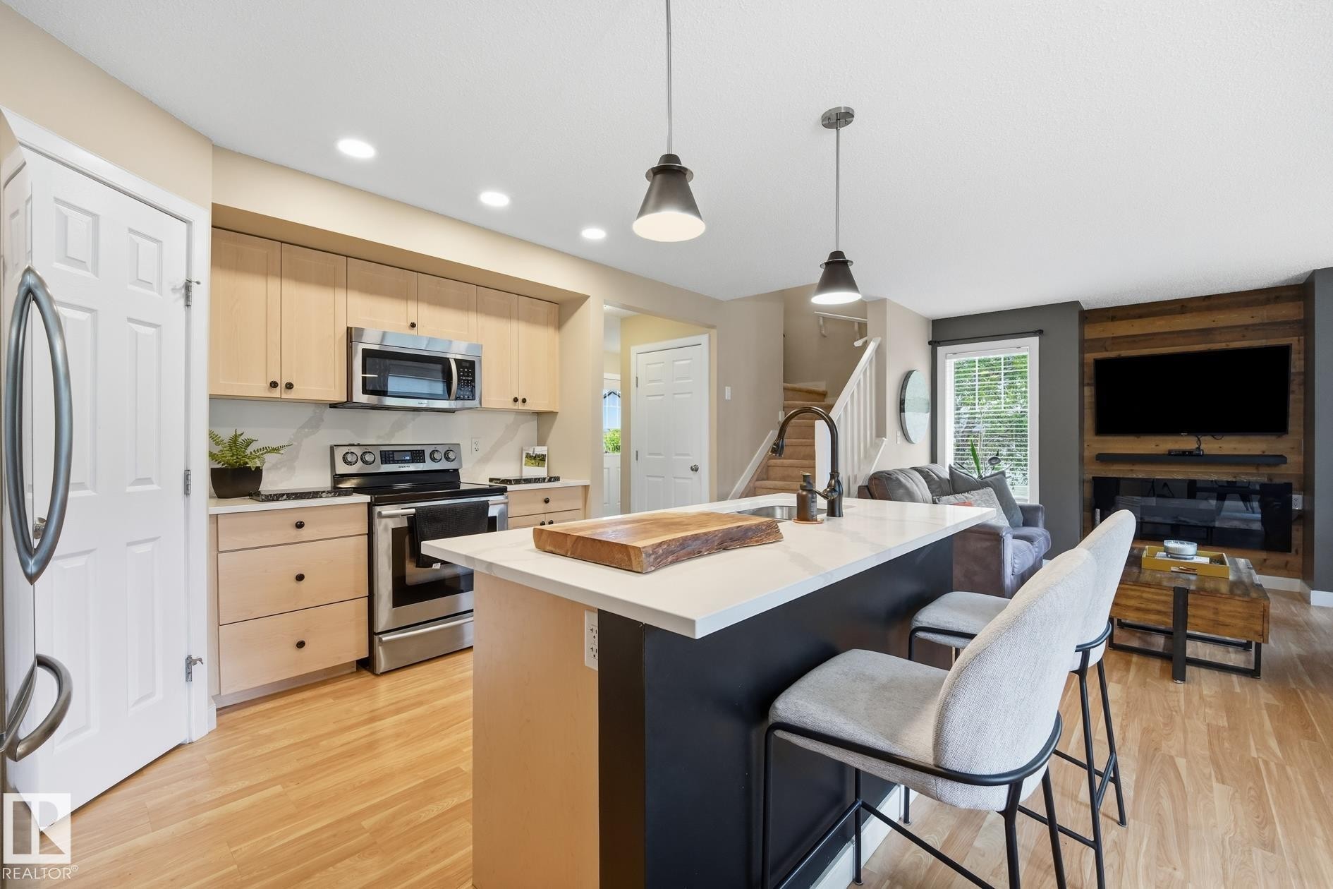 Well-appointed kitchen featuring light wood-finish cabinetry, stainless steel appliances, and a central island with a sink and seating - 20007 131 Avenue Nw, Edmonton, AB