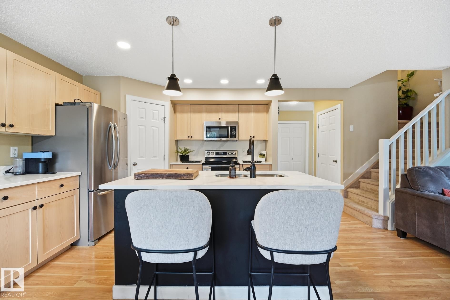 Kitchen featuring a center island with pendant lighting, stainless steel appliances, and light wood-finish cabinetry - 20007 131 Avenue Nw, Edmonton, AB