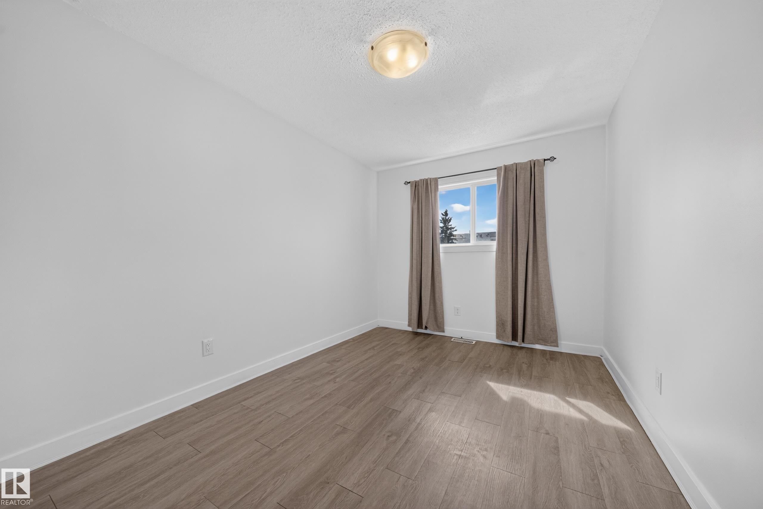 Wood-finish flooring, white walls, and a window with a neutral curtain rod - 155 Marlborough Place Nw, Edmonton, AB