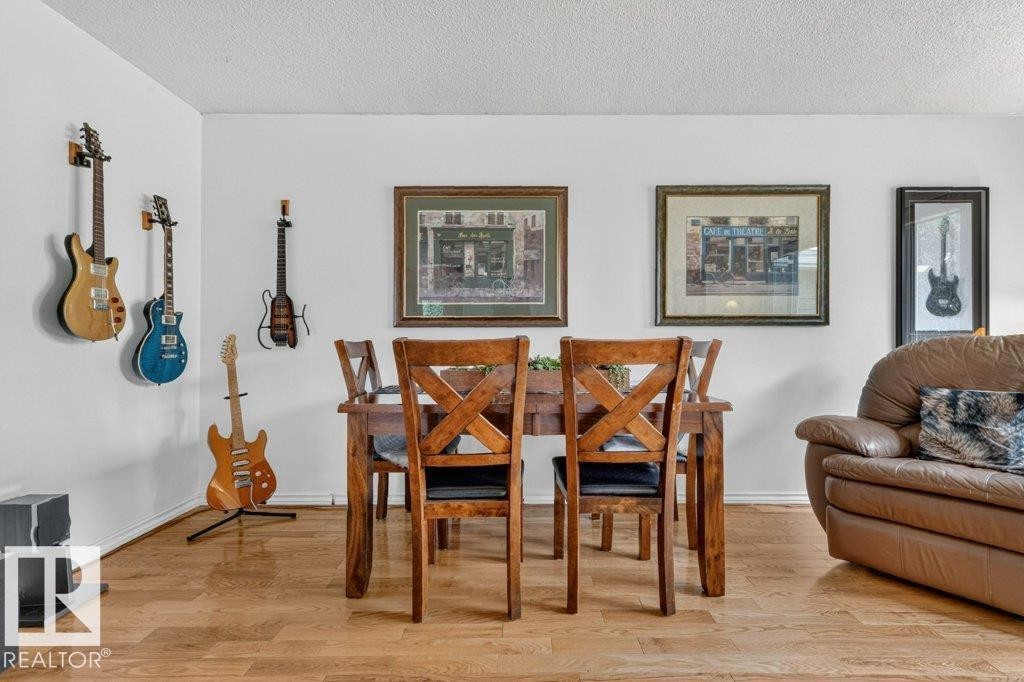 Dining area featuring wood-finish flooring, a wood dining table, and white painted walls - 11131 35A Avenue Nw, Edmonton, AB - Indoor