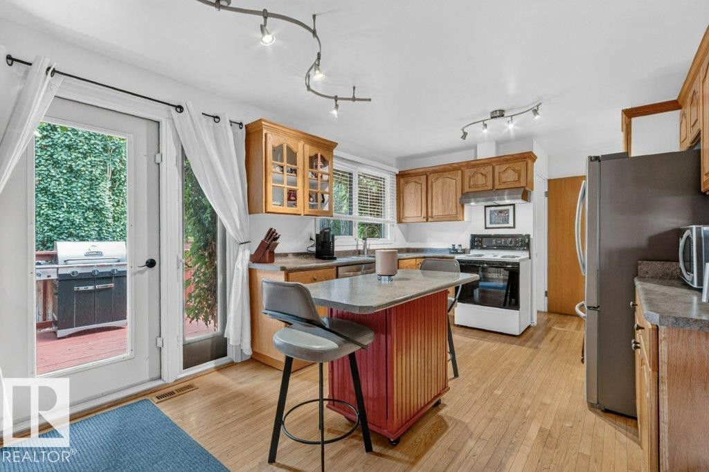 Kitchen with wood-finish flooring, wood cabinetry, and a central island with a countertop - 11131 35A Avenue Nw, Edmonton, AB - Indoor Photo Showing Kitchen