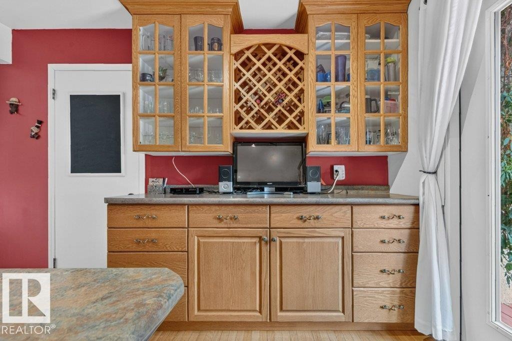 Wood-finish cabinetry with glass-front upper cabinets and an integrated wine rack - 11131 35A Avenue Nw, Edmonton, AB - Indoor Photo Showing Bedroom