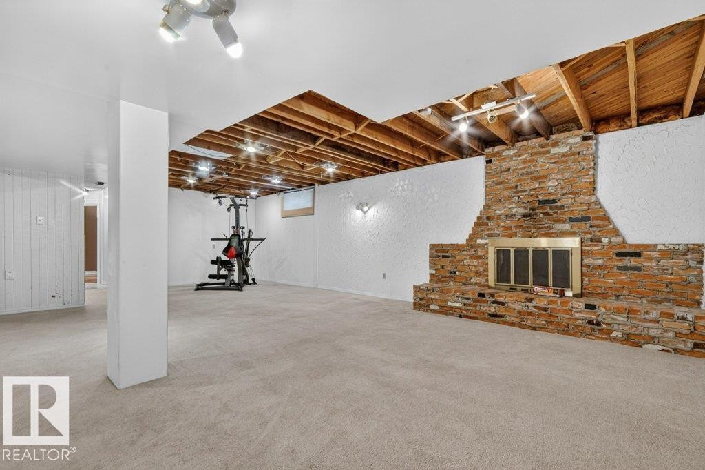 Spacious finished basement featuring light-colored carpeting, white textured walls, and exposed wood ceiling joists - 11131 35A Avenue Nw, Edmonton, AB - Indoor Photo Showing Basement