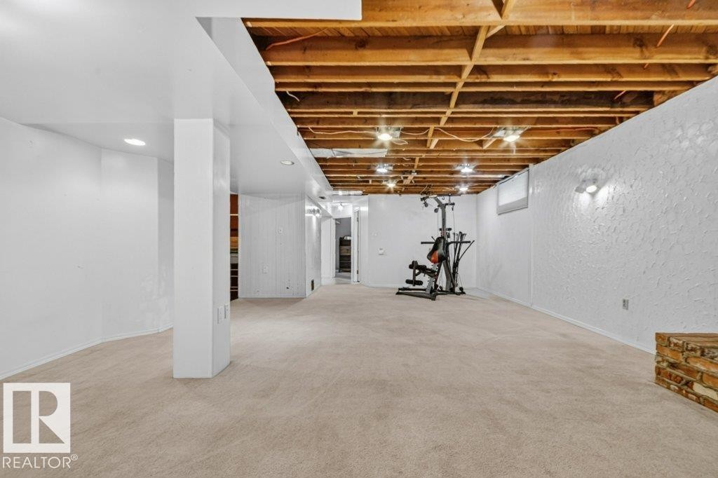 Expansive lower level featuring neutral carpeting, a partially finished ceiling with exposed wood beams, and recessed lighting - 11131 35A Avenue Nw, Edmonton, AB - Indoor Photo Showing Basement