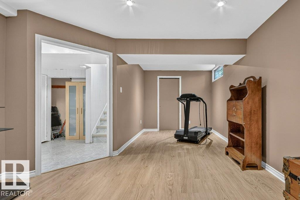 Finished lower level with wood-finish flooring, recessed lighting, a window, and a doorway leading to a tiled area with stairs - 11131 35A Avenue Nw, Edmonton, AB - Indoor