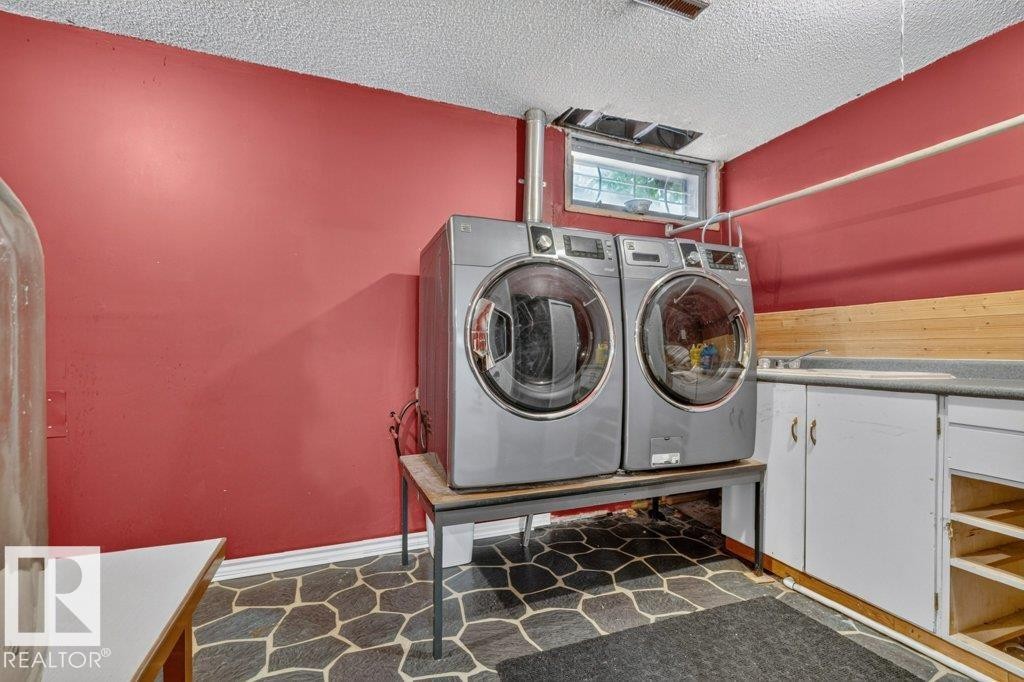 Dedicated laundry area featuring a window, built-in cabinetry, countertop space, and stone-patterned flooring - 11131 35A Avenue Nw, Edmonton, AB - Indoor Photo Showing Laundry Room