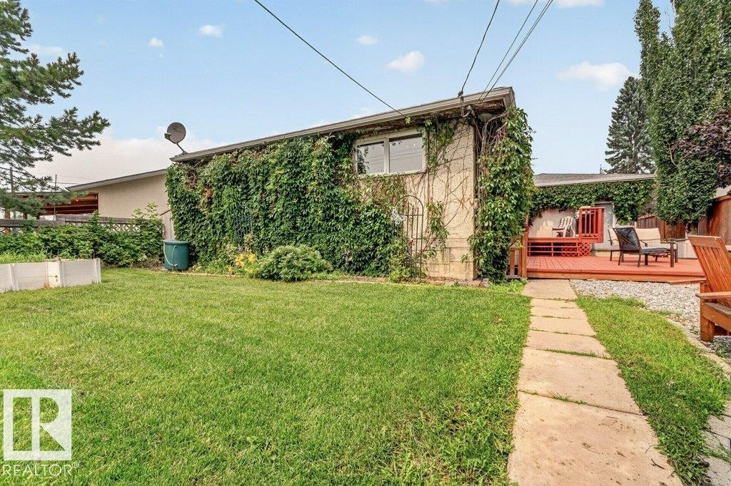 Expansive backyard featuring a green lawn, concrete stepping stone path, and a red-toned wood deck - 11131 35A Avenue Nw, Edmonton, AB - Outdoor