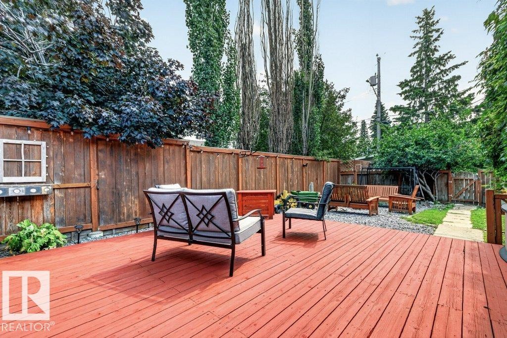 Expansive backyard featuring a large red-stained wood deck, perimeter wood fencing, and mature trees - 11131 35A Avenue Nw, Edmonton, AB - Outdoor With Deck Patio Veranda