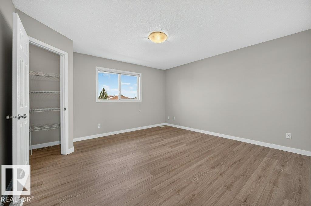 Wood-finish flooring, neutral gray walls, white trim, and a window with a natural light exposure - #26 2816 34 Av Nw, Edmonton, AB