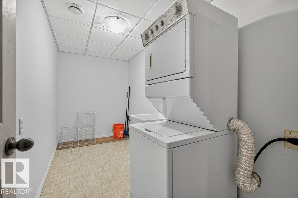 Dedicated laundry area featuring a stacked washer and dryer, utility sink, and tiled flooring - #26 2816 34 Av Nw, Edmonton, AB