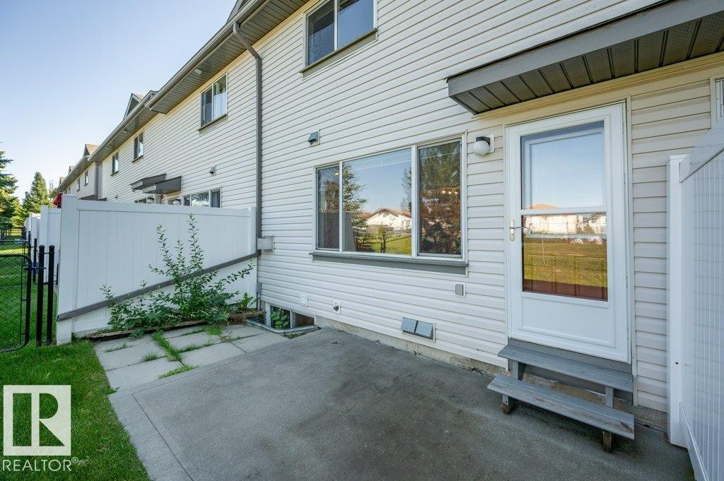 Private patio area with concrete surfacing, white vinyl siding, and a security screen door - #26 2816 34 Av Nw, Edmonton, AB