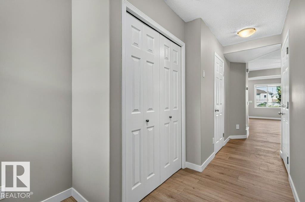 Hallway featuring wood-finish flooring, light gray walls, white trim, and recessed lighting - #26 2816 34 Av Nw, Edmonton, AB