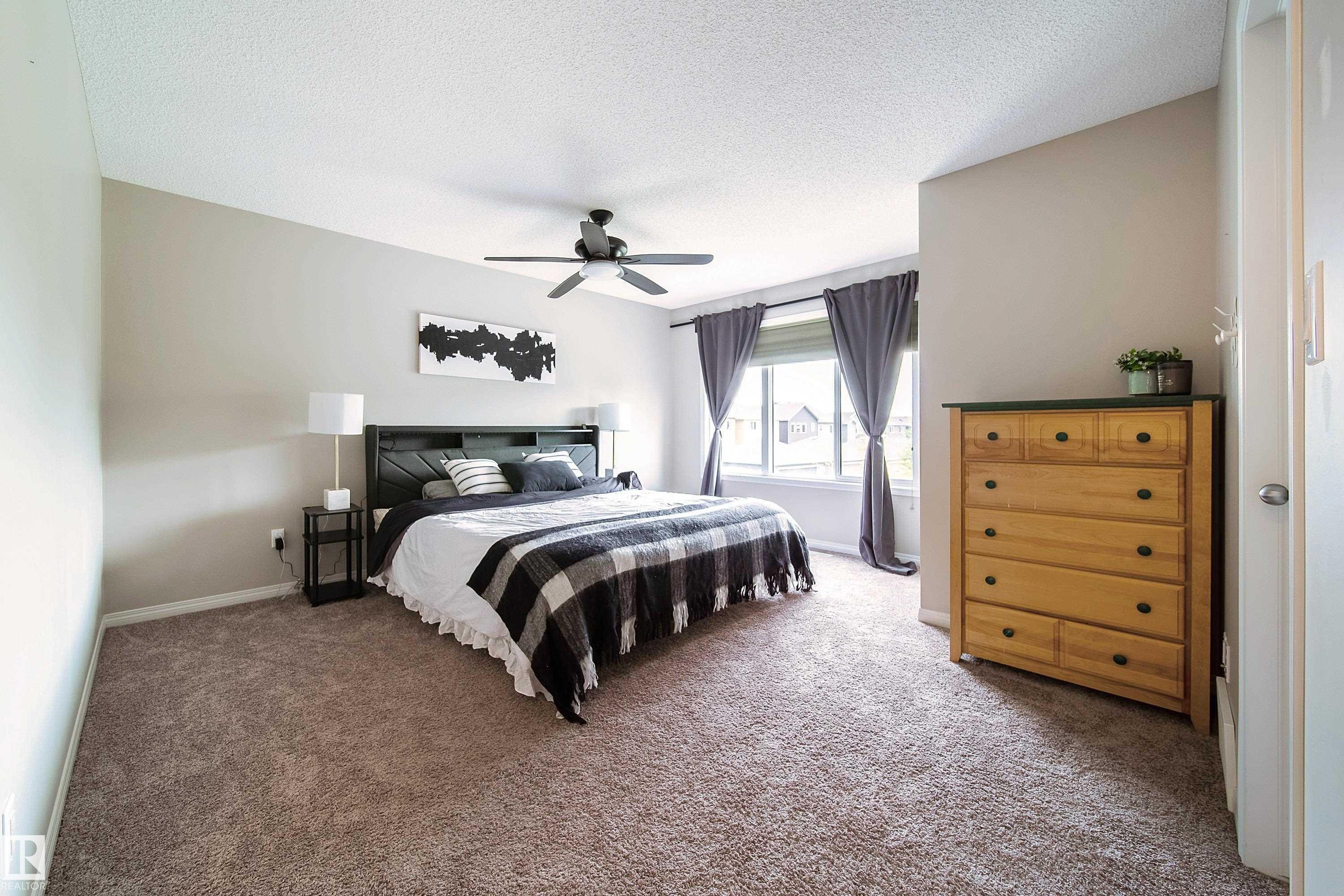 Carpeted room featuring a ceiling fan, window with curtain rod, and neutral wall tones - 3211 Cherry Crescent Sw, Edmonton, AB