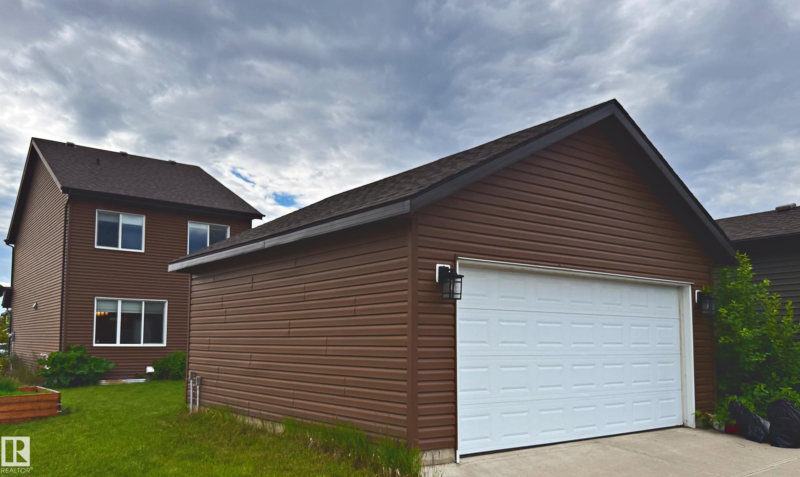 Brick and vinyl-sided two-story home with attached two-car garage featuring a white overhead door - 3211 Cherry Crescent Sw, Edmonton, AB