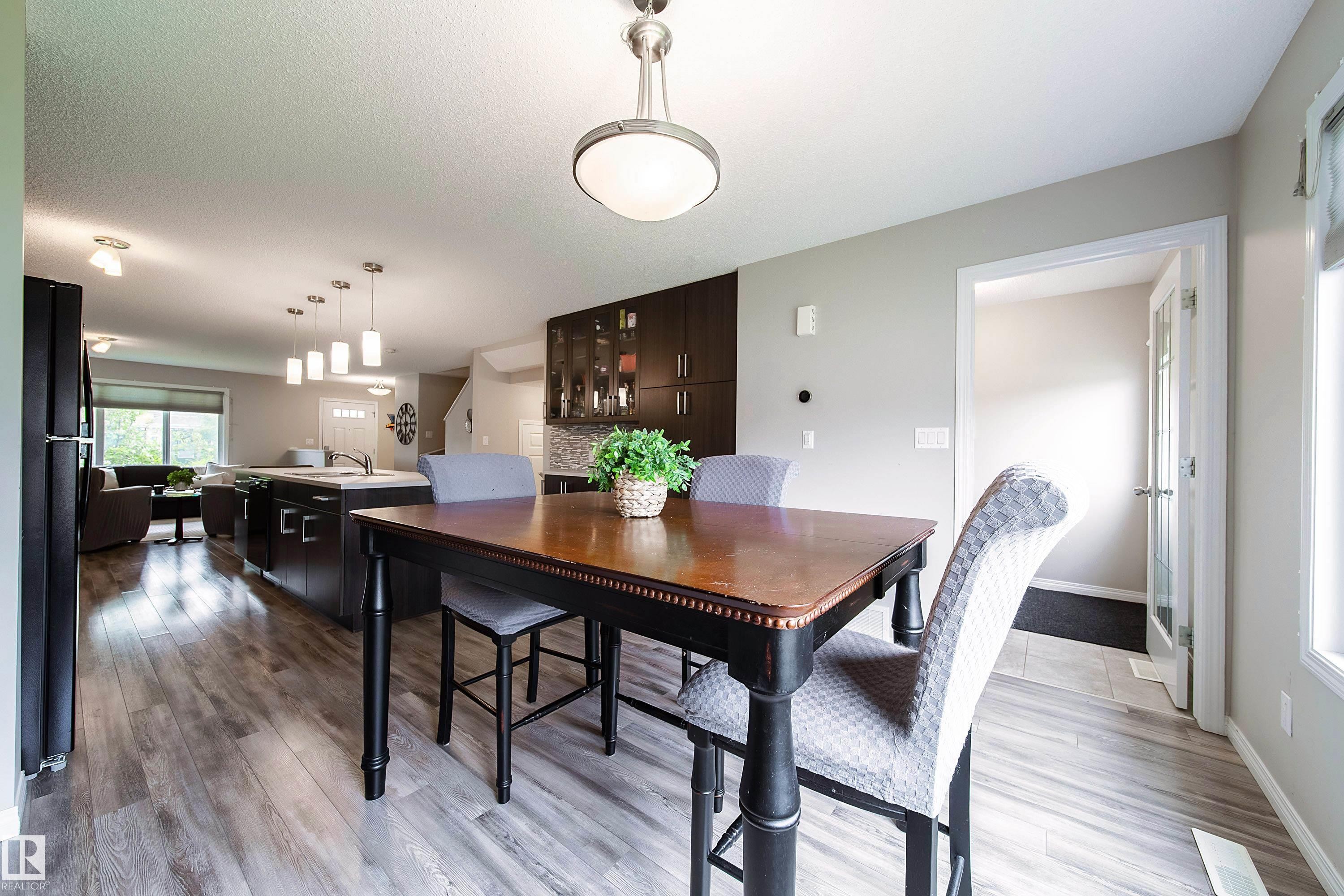 Recessed lighting, wood-finish flooring, and pendant lighting illuminate the open-concept living space - 3211 Cherry Crescent Sw, Edmonton, AB