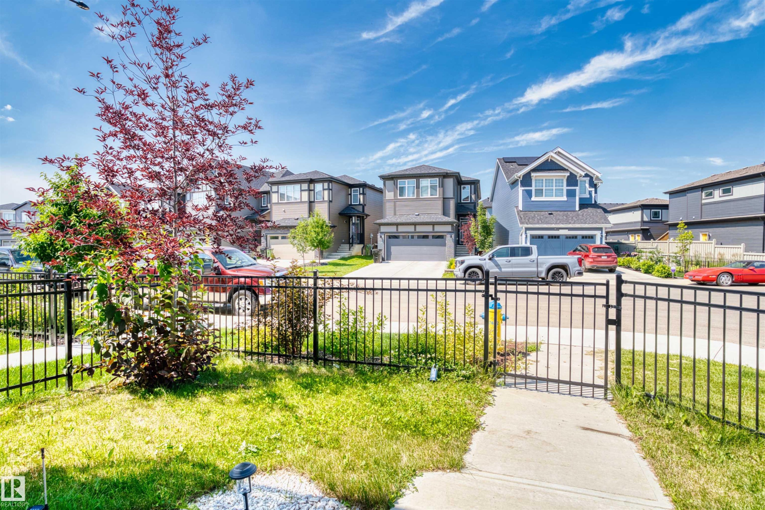 Manicured front yard with a black metal fence and mature landscaping - 8047 227 Street Nw, Edmonton, AB