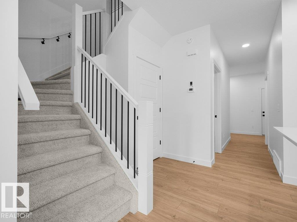 White walls complement wood-finish flooring and a carpeted staircase - 912 17 Ave Nw, Edmonton, AB