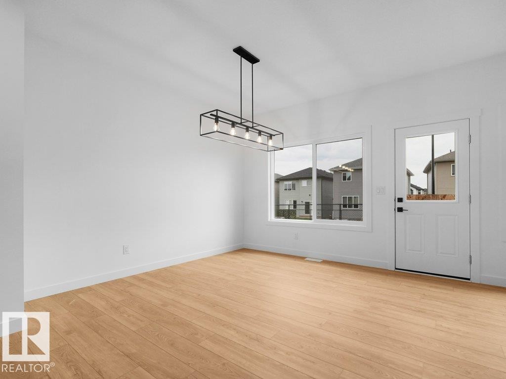 Wood-finish flooring, white walls, and a contemporary linear pendant light fixture - 912 17 Ave Nw, Edmonton, AB