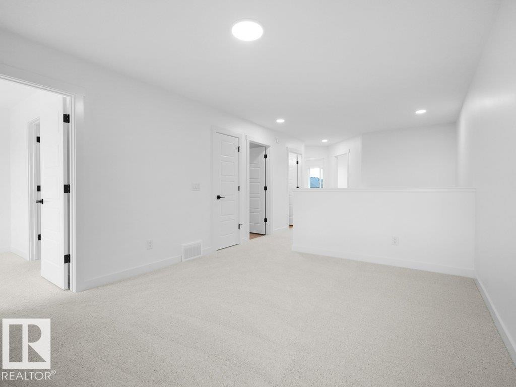 White painted walls, recessed lighting, white doors with matte black hardware, and light-colored carpeting - 912 17 Ave Nw, Edmonton, AB