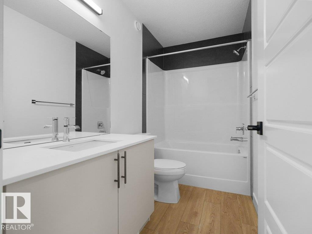 Bathroom featuring a single vanity with an integrated sink, polished chrome faucet, and a spacious mirror - 912 17 Ave Nw, Edmonton, AB