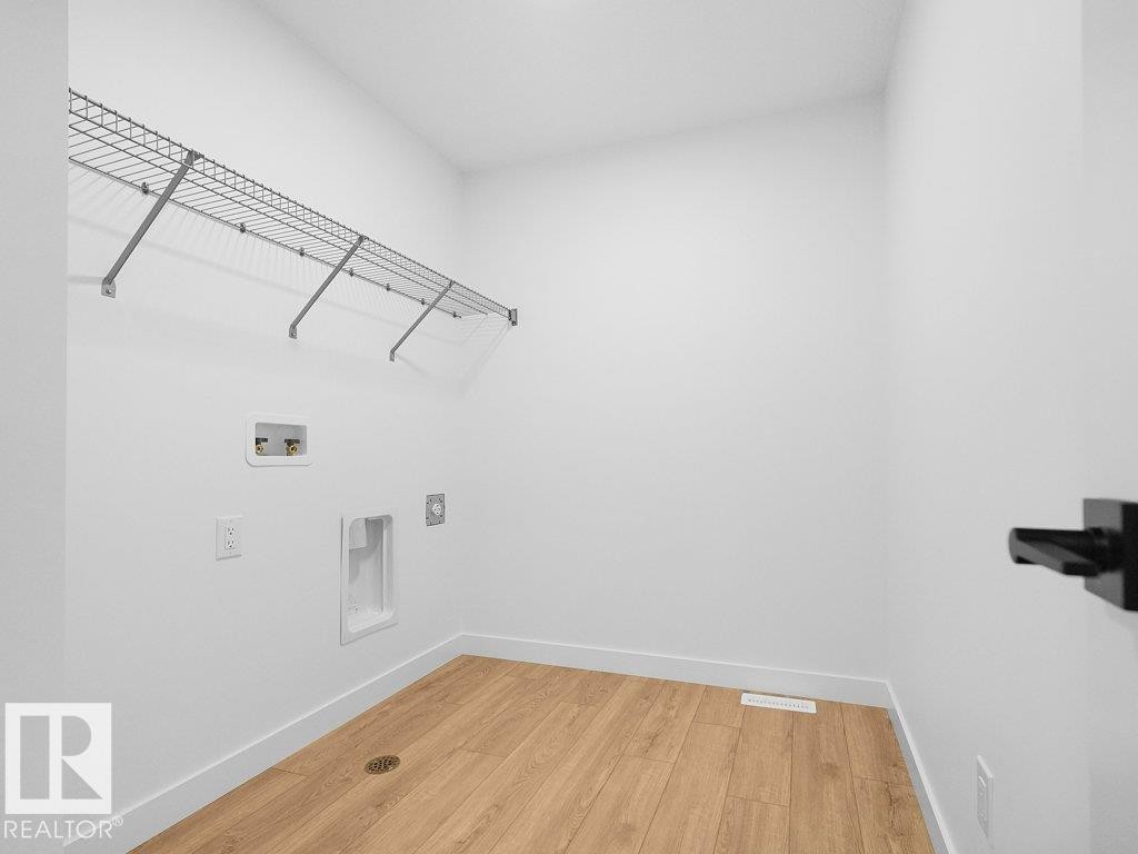 Laundry area featuring a wire storage shelf, wood-finish flooring, and a floor drain - 912 17 Ave Nw, Edmonton, AB