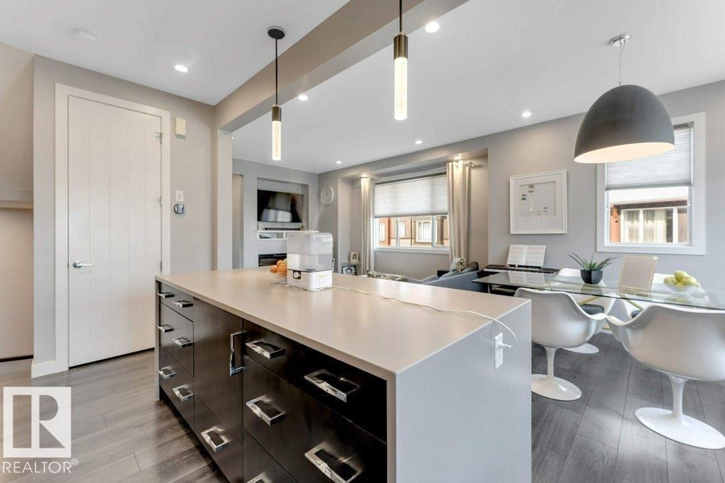 Kitchen island with a light-toned countertop and dark wood-finish cabinetry - #45 16903 68 St Nw, Edmonton, AB