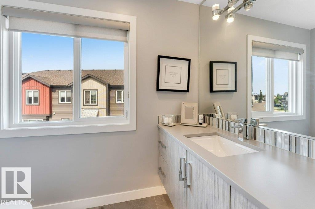 White framed window, light gray wall paint, built-in vanity with light wood-finish cabinetry, integrated sink, and polished chrome faucet - #45 16903 68 St Nw, Edmonton, AB