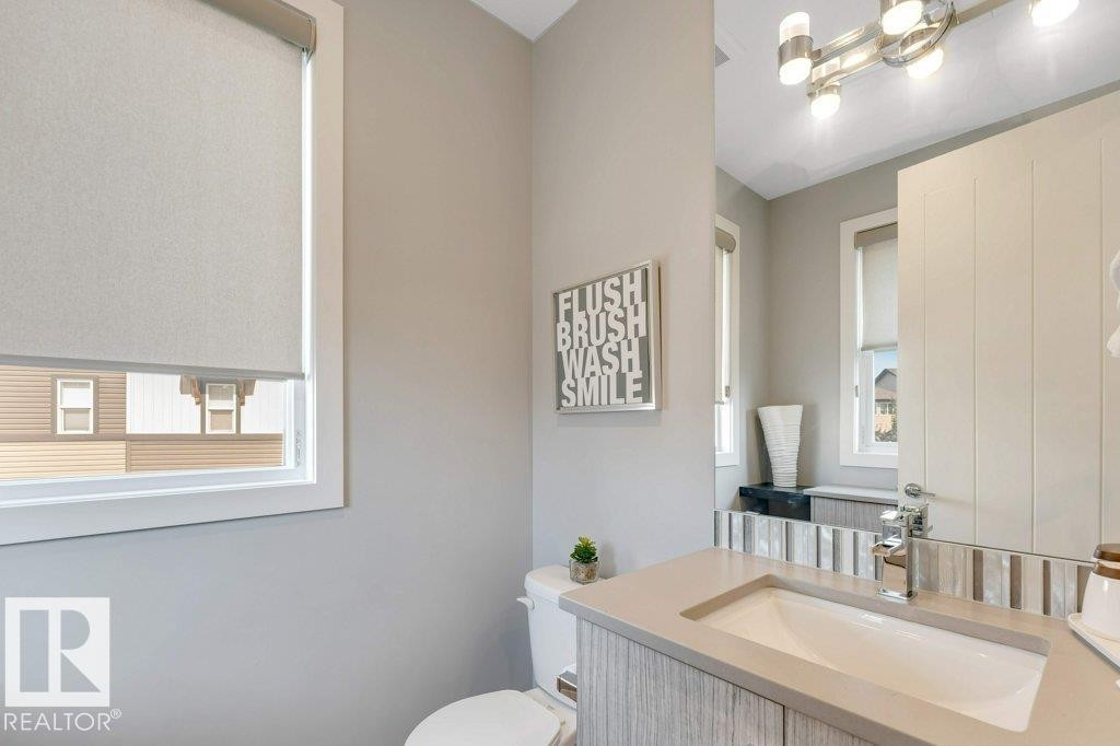 Vanity with integrated sink, stone countertop, wood-finish cabinetry, chrome faucet, and decorative tile backsplash - #45 16903 68 St Nw, Edmonton, AB