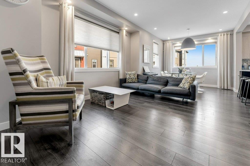 Wood-finish flooring throughout, recessed ceiling lighting, large windows with blinds, and a built-in kitchen peninsula - #45 16903 68 St Nw, Edmonton, AB