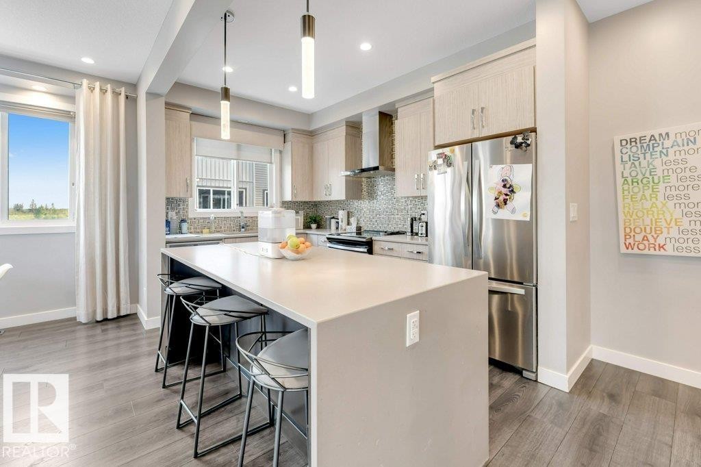 Kitchen featuring light wood-finish cabinetry, stainless steel appliances, and a mosaic tile backsplash - #45 16903 68 St Nw, Edmonton, AB