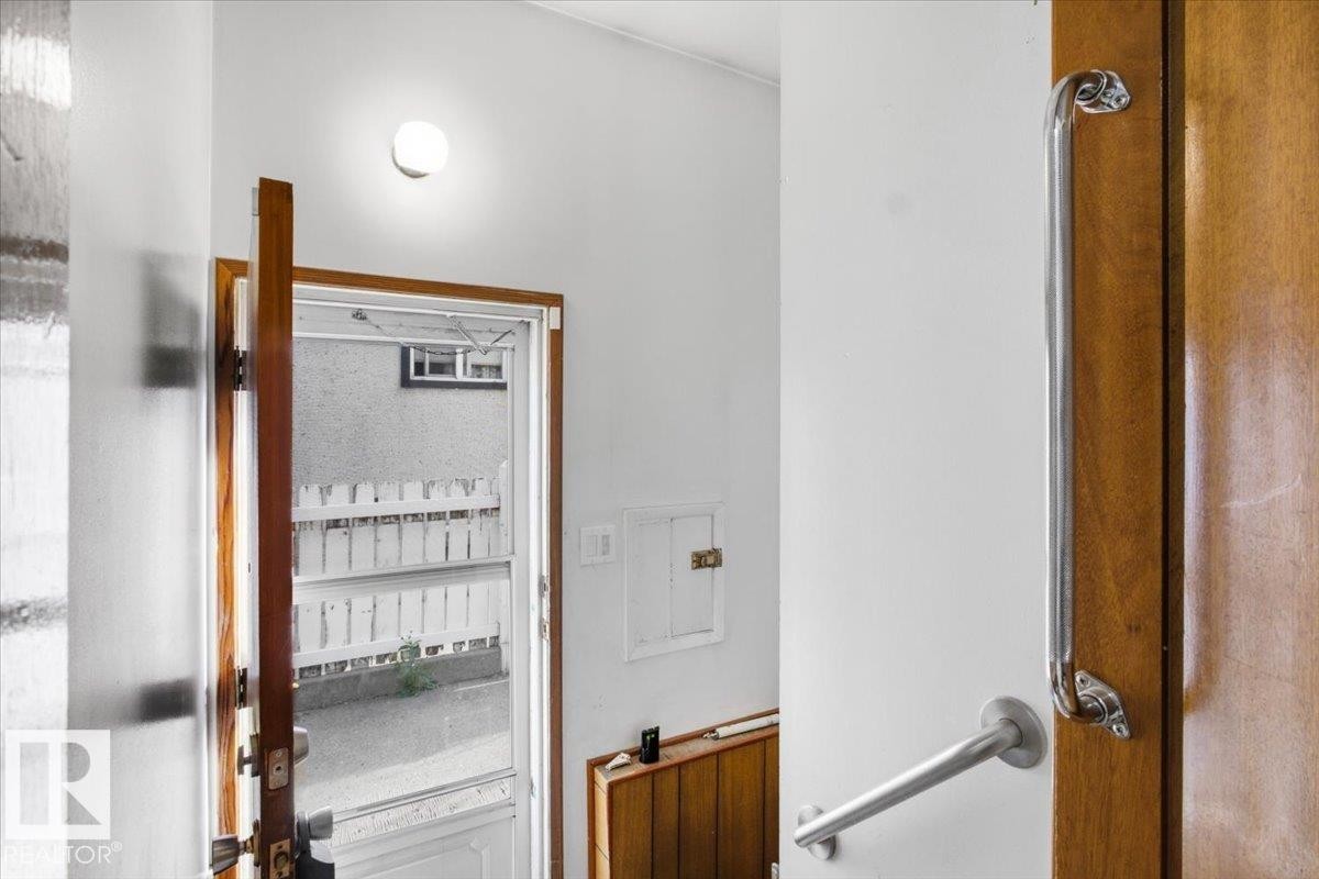 Wood-finish interior door, recessed wall paneling, and a white picket fence - 13235 82 Street Nw, Edmonton, AB