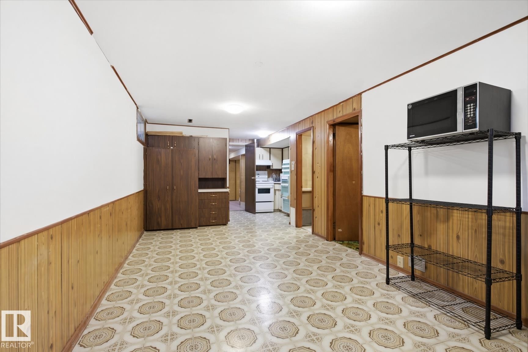 Vinyl flooring with a geometric pattern, wood-paneled walls, and built-in cabinetry - 13235 82 Street Nw, Edmonton, AB