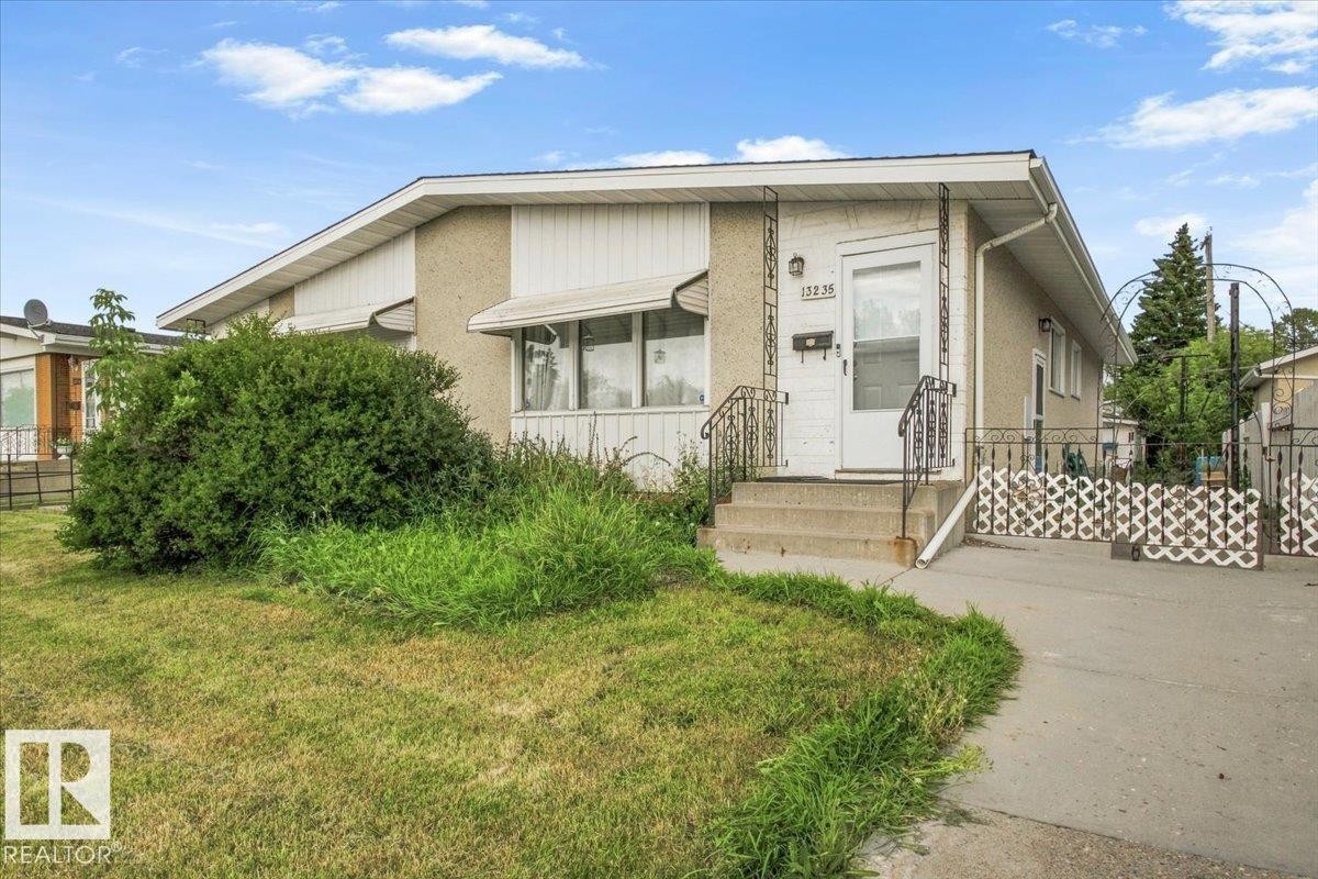 Stucco exterior with contrasting white siding accents, concrete steps with wrought iron railings, and an asphalt driveway - 13235 82 Street Nw, Edmonton, AB