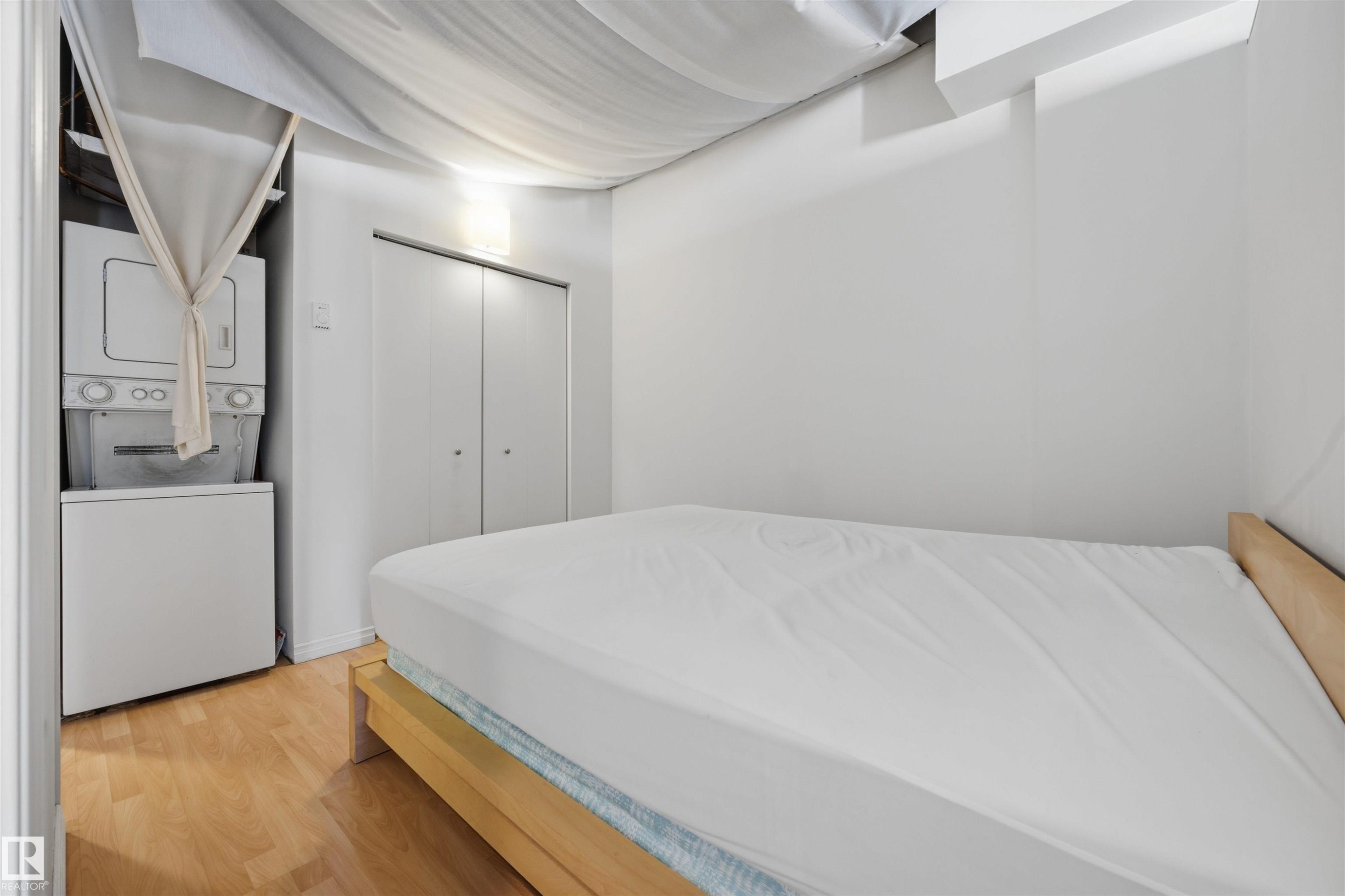 Wood-finish flooring with a white washer and dryer stack - #1313 10024 Jasper Av Nw, Edmonton, AB