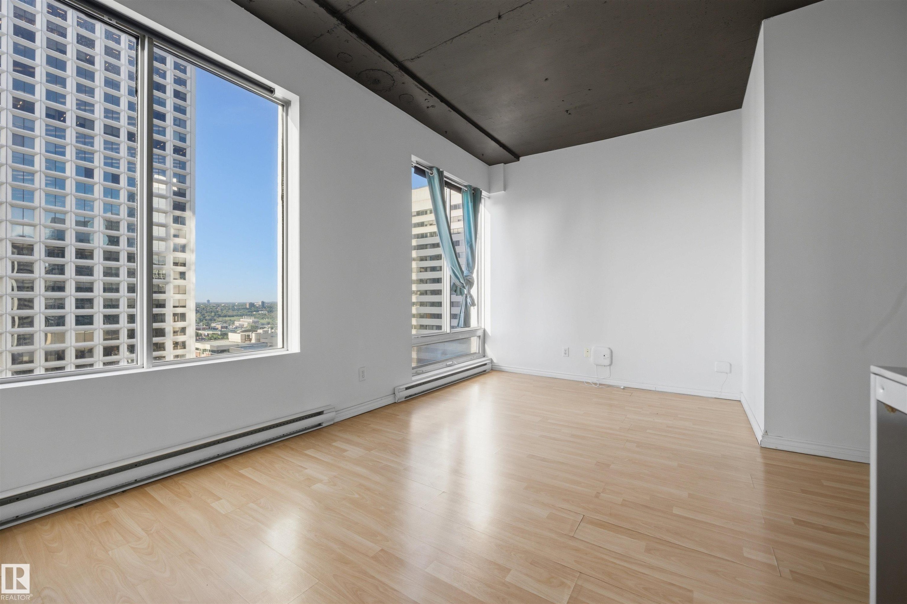 Expansive windows, light wood-finish flooring, white wall finishes, and exposed dark ceiling - #1313 10024 Jasper Av Nw, Edmonton, AB