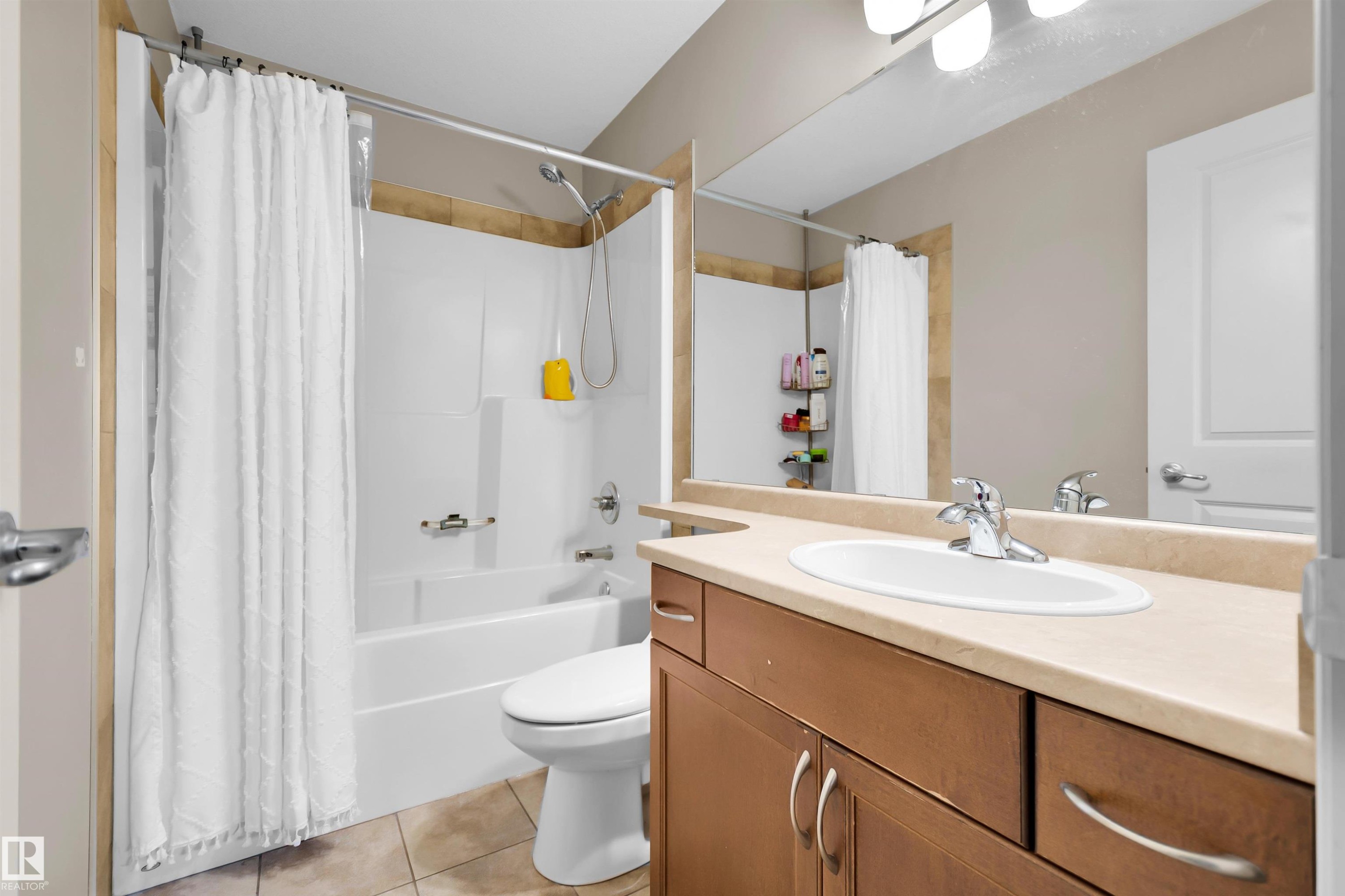 White drop-in bathtub with shower, wood-finish vanity with countertop, oval sink, and chrome faucet - #5 5120 164 Av Nw, Edmonton, AB