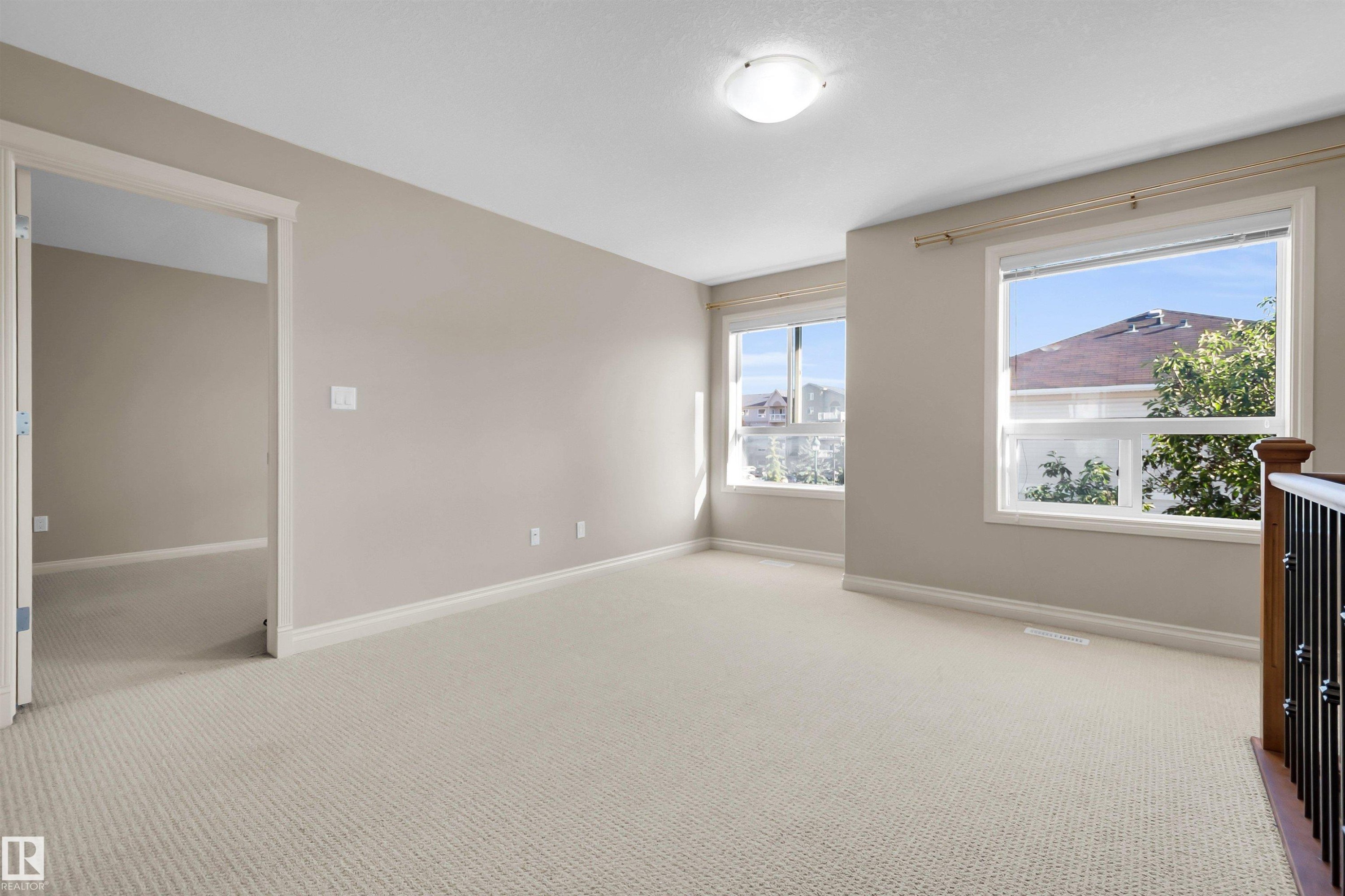 Carpeted flooring, neutral wall tones, multiple windows, overhead lighting, and built-in railing - #5 5120 164 Av Nw, Edmonton, AB
