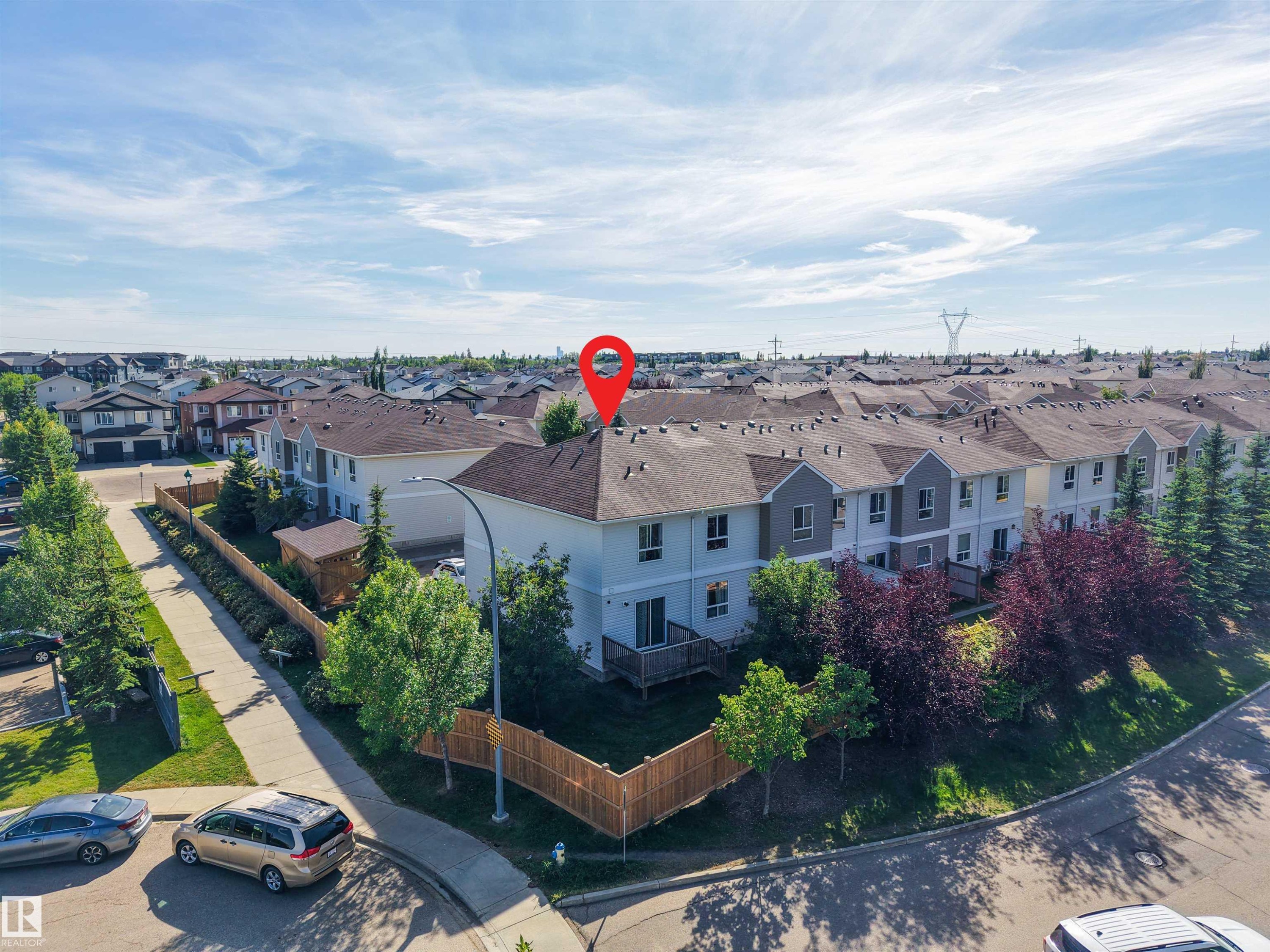 Residential property featuring a grey shingled roof, light-colored siding, and a wooden privacy fence - #5 5120 164 Av Nw, Edmonton, AB