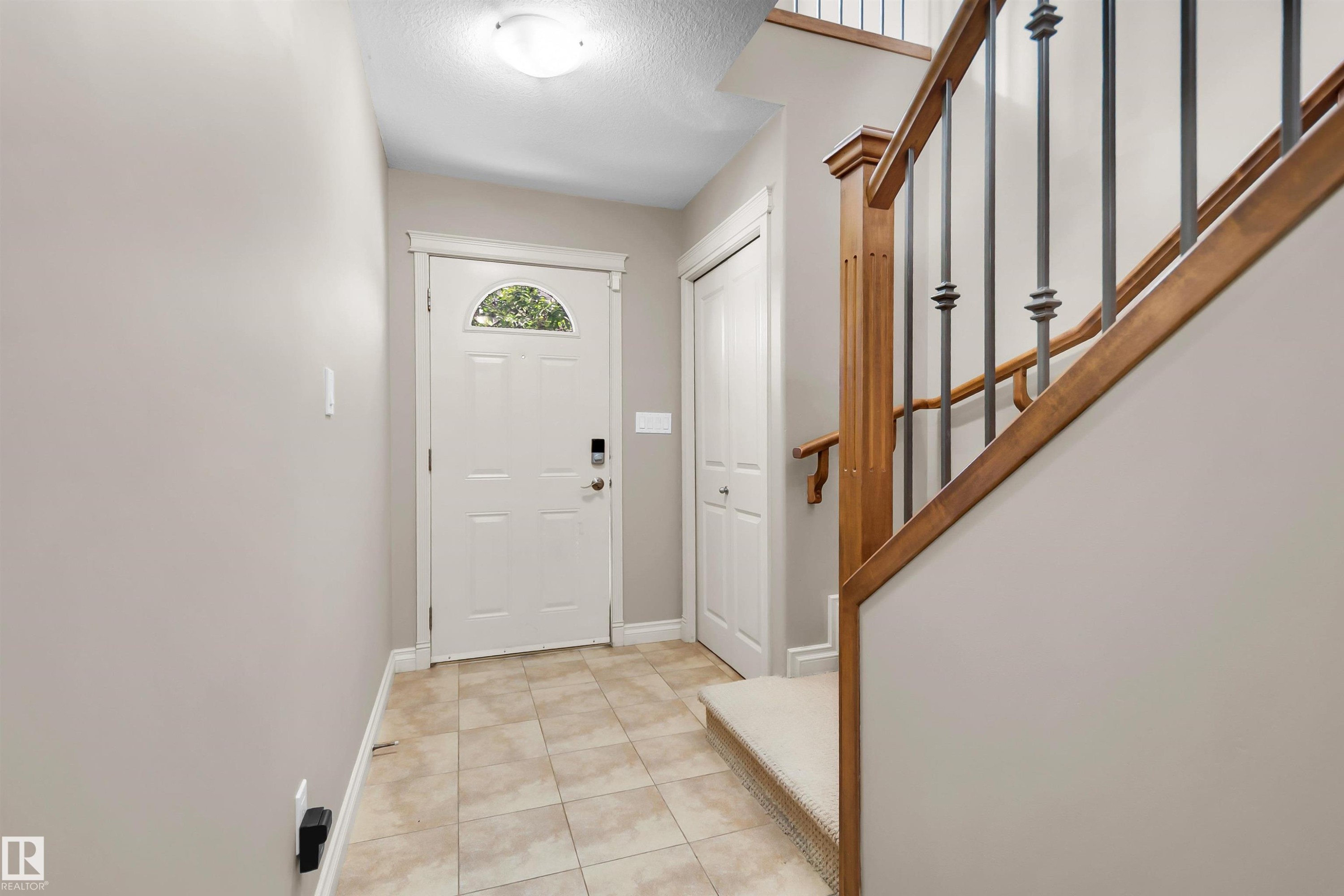 Tiled entry flooring with a front entry door featuring an arched window detail - #5 5120 164 Av Nw, Edmonton, AB