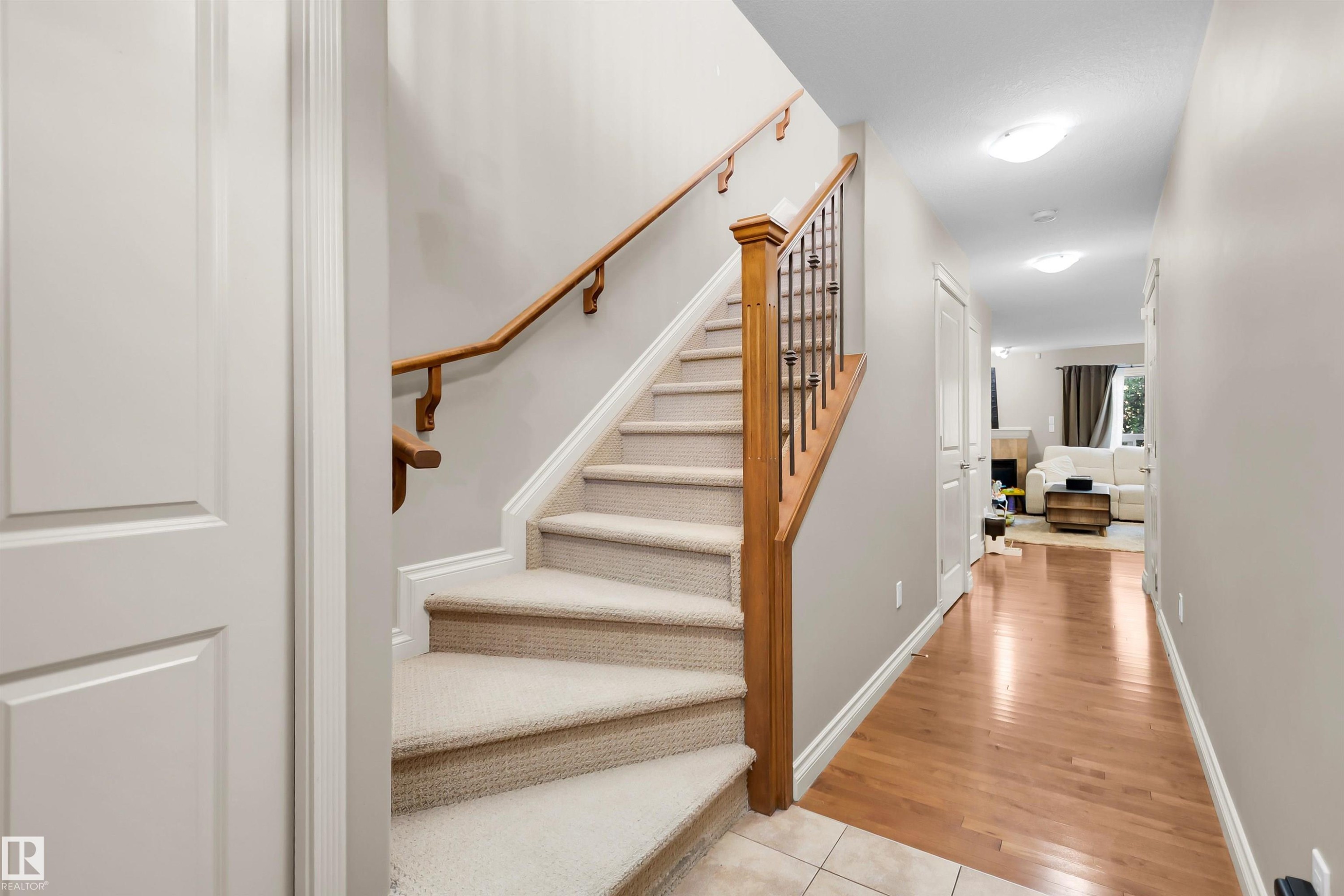 Carpeted staircase with wood banister and wrought iron spindles - #5 5120 164 Av Nw, Edmonton, AB
