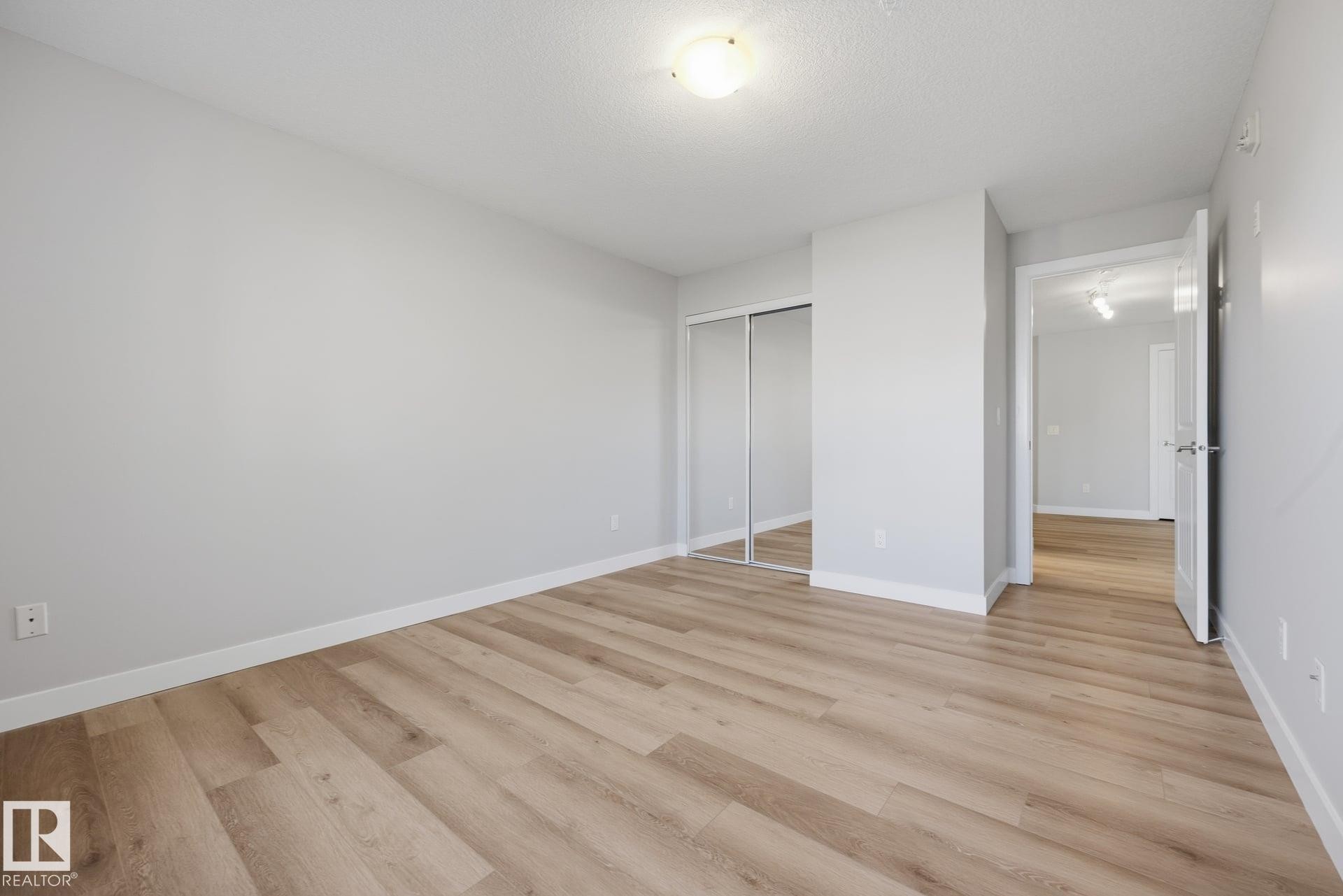 Light wood-finish flooring, white walls, and a ceiling-mounted light fixture - #122 240 Spruce Ridge Rd, Spruce Grove, AB
