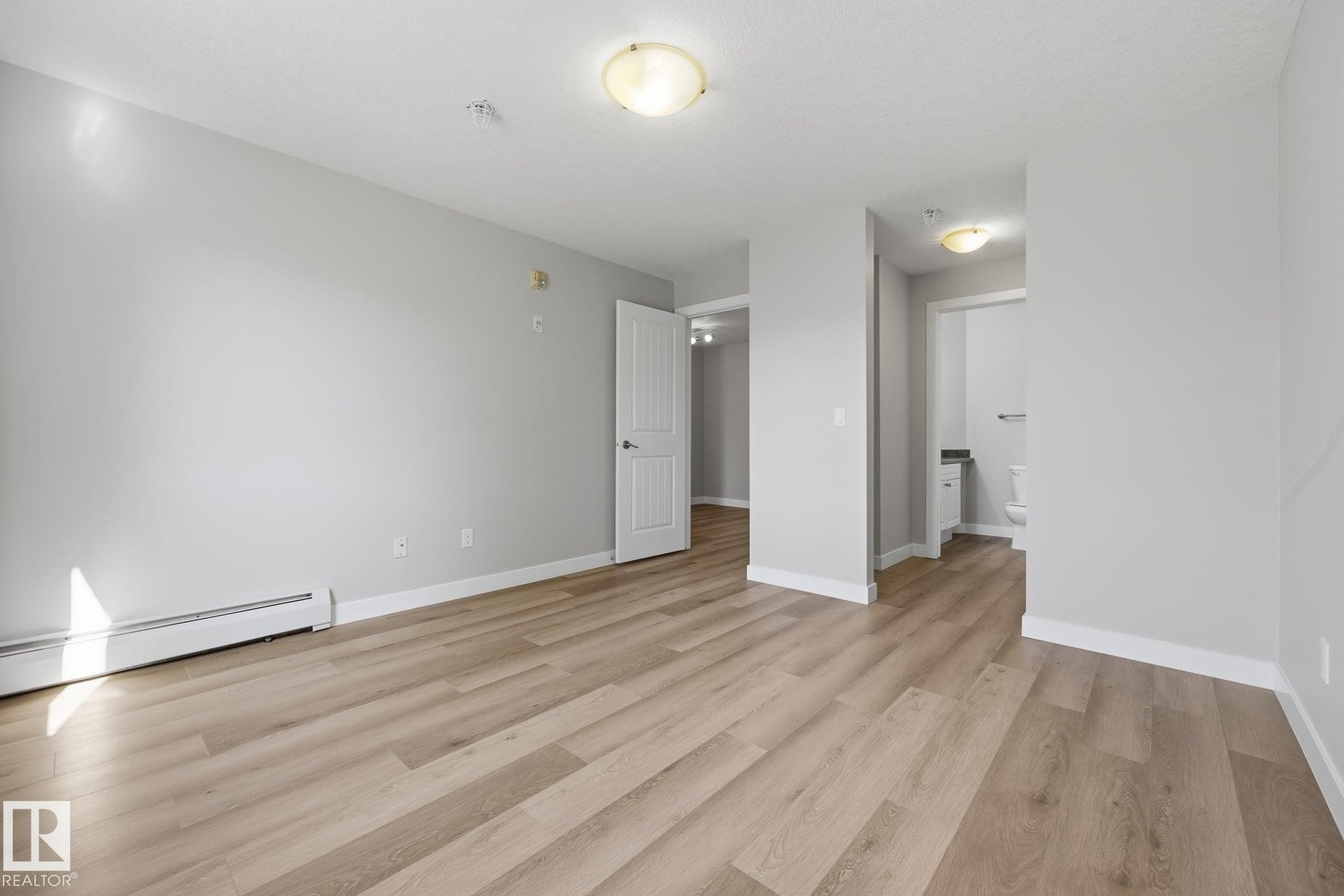 Wood-finish flooring, white trim, flush mount lighting, and interior doors - #122 240 Spruce Ridge Rd, Spruce Grove, AB