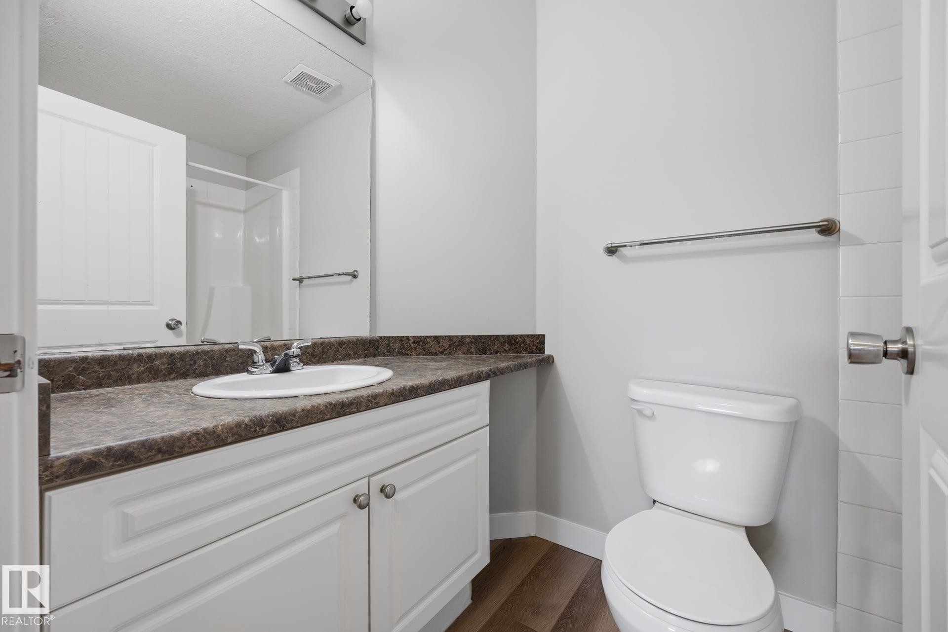 White vanity with paneled doors, integrated sink, and dark countertop - #122 240 Spruce Ridge Rd, Spruce Grove, AB